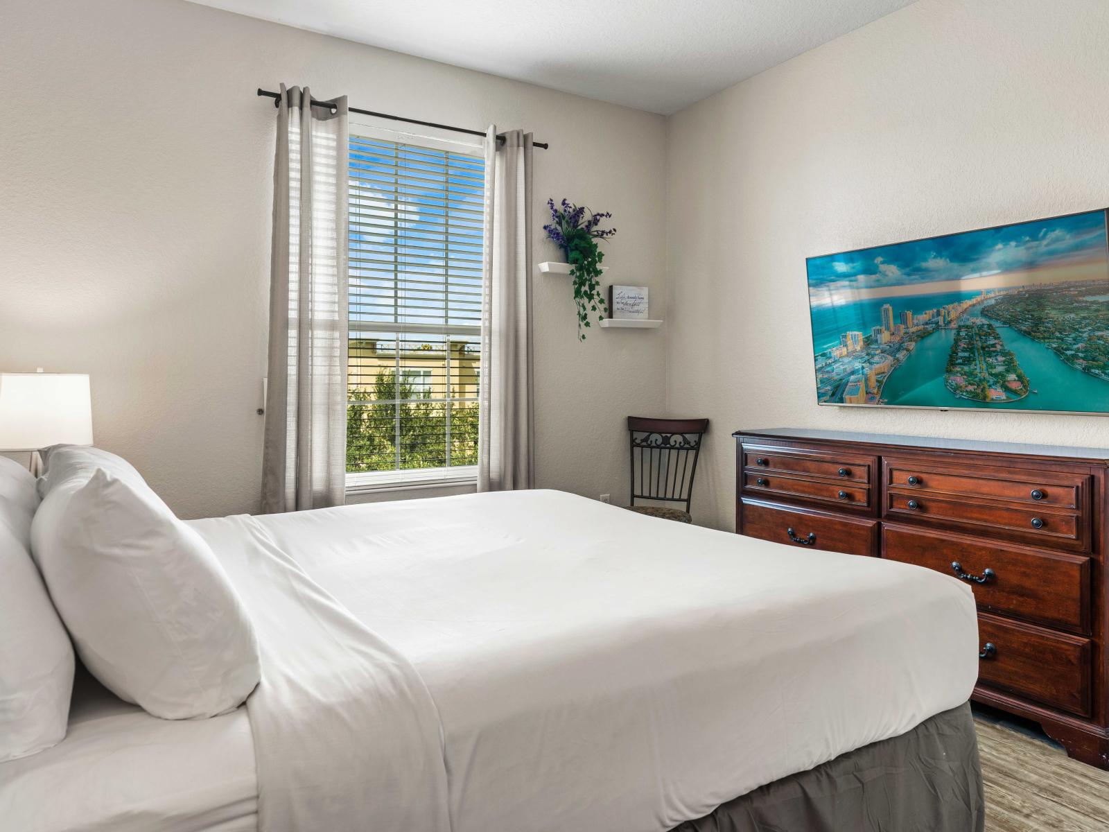 - Bedroom featuring a king-sized bed, an attached bath perfect for a convenient stay - Generous space is available along with a wall-mounted Smart TV for entertainment - Large window allows natural light to brighten the room paired with stylish decor