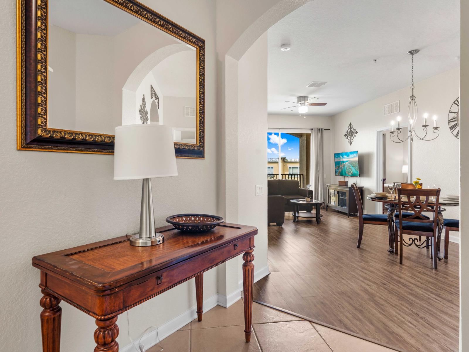 - An entrance with a stylish console table and elegant decor setting the tone for a cozy stay - Large mirror enhances the space leading into an open living and dining area - Arched doorways add a touch of charm as you enter the main living space