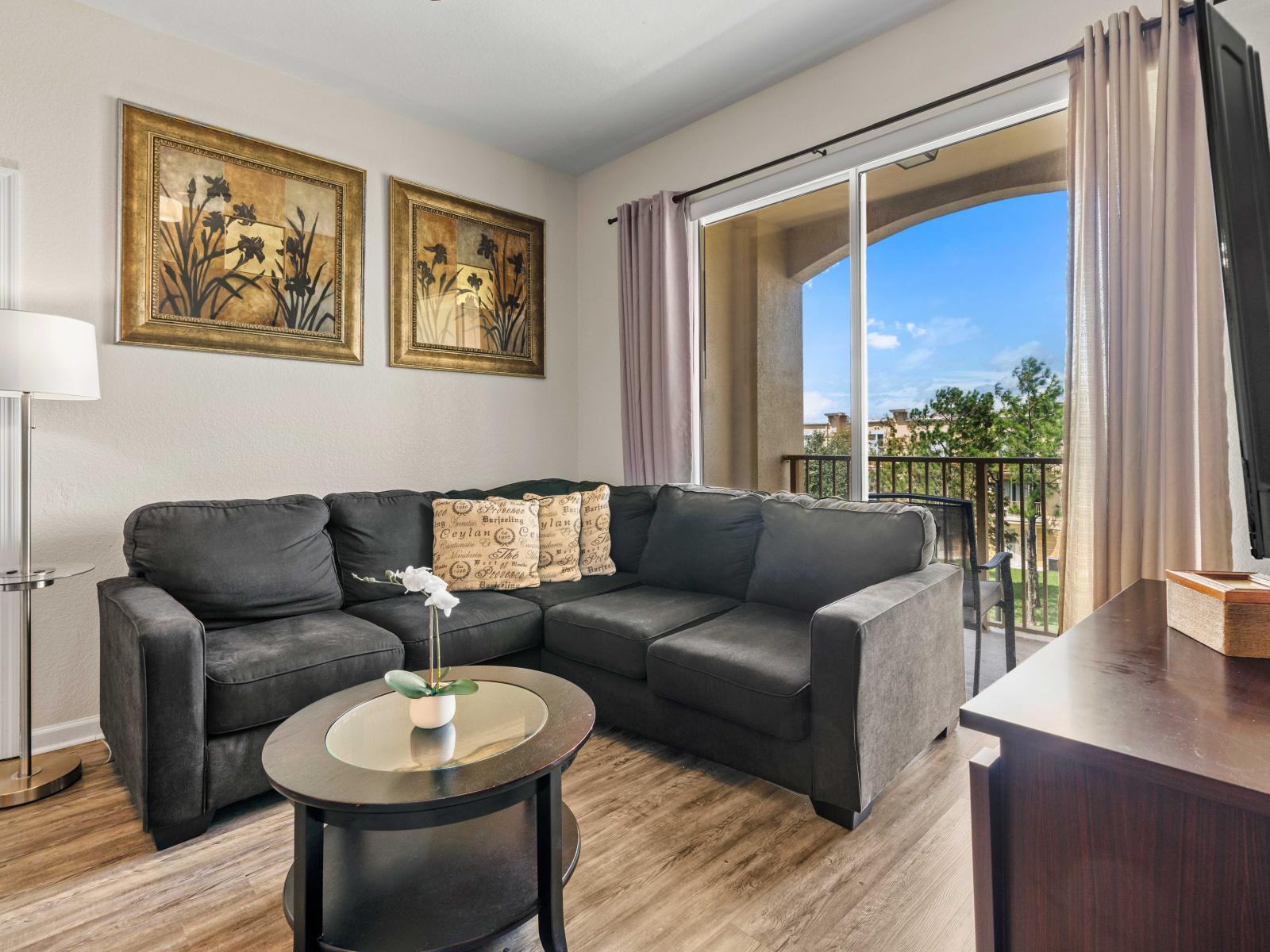 - Beautiful living room with a plush corner sofa ideal for relaxing & entertainment - Living room features access to the balcony making it easy to enjoy outdoor view - Decorated with tasteful artwork and a chic coffee table creates a warm space