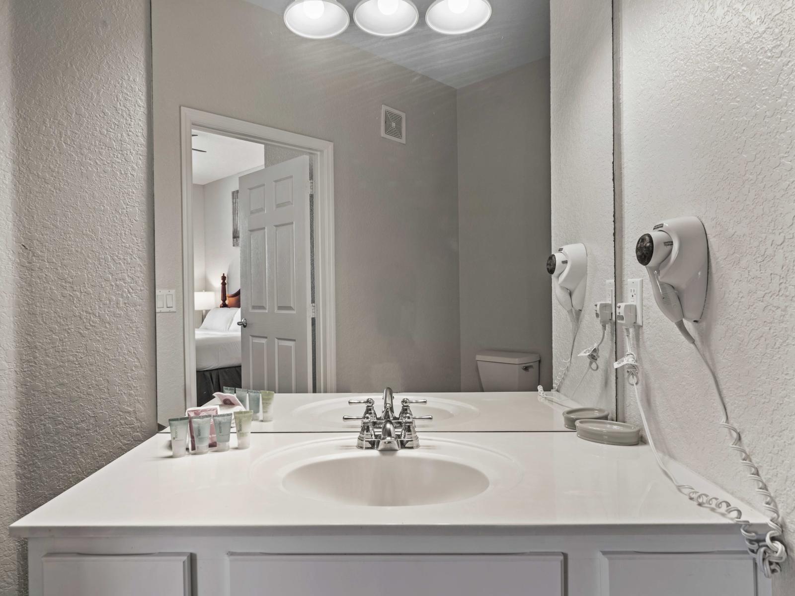 - Bathroom featuring a modern vanity, providing plenty of space for personal care - Large mirror and bright lighting offers elegant setting for your daily routine - Convenient amenities like a wall-mounted hairdryer ensure a comfortable stay