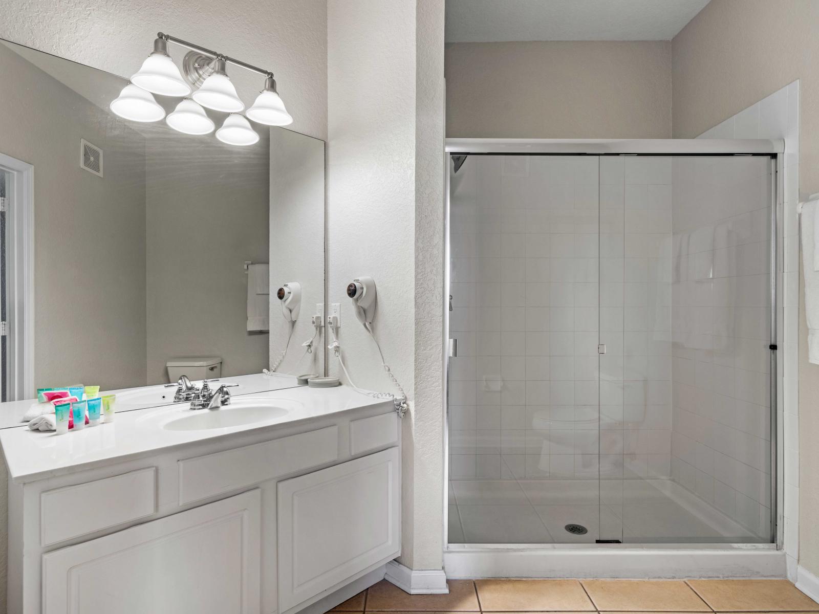 - Spacious bathroom featuring a large vanity and glass-enclosed walk-in shower - Well-lit with modern fixtures providing a functional space for your daily routine - Stocked with plush towels and generous counter space for your toiletries &essentials