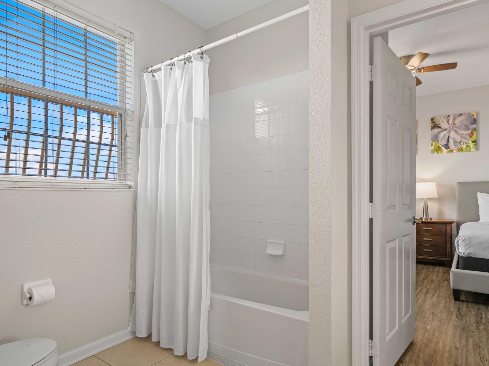 - Bathroom featuring a convenient bathtub and shower combo, ideal for quick rinses - A window allows natural light to brighten the space, creating a fresh and airy atmosphere - Located adjacent to the bedroom for easy access and added comfort