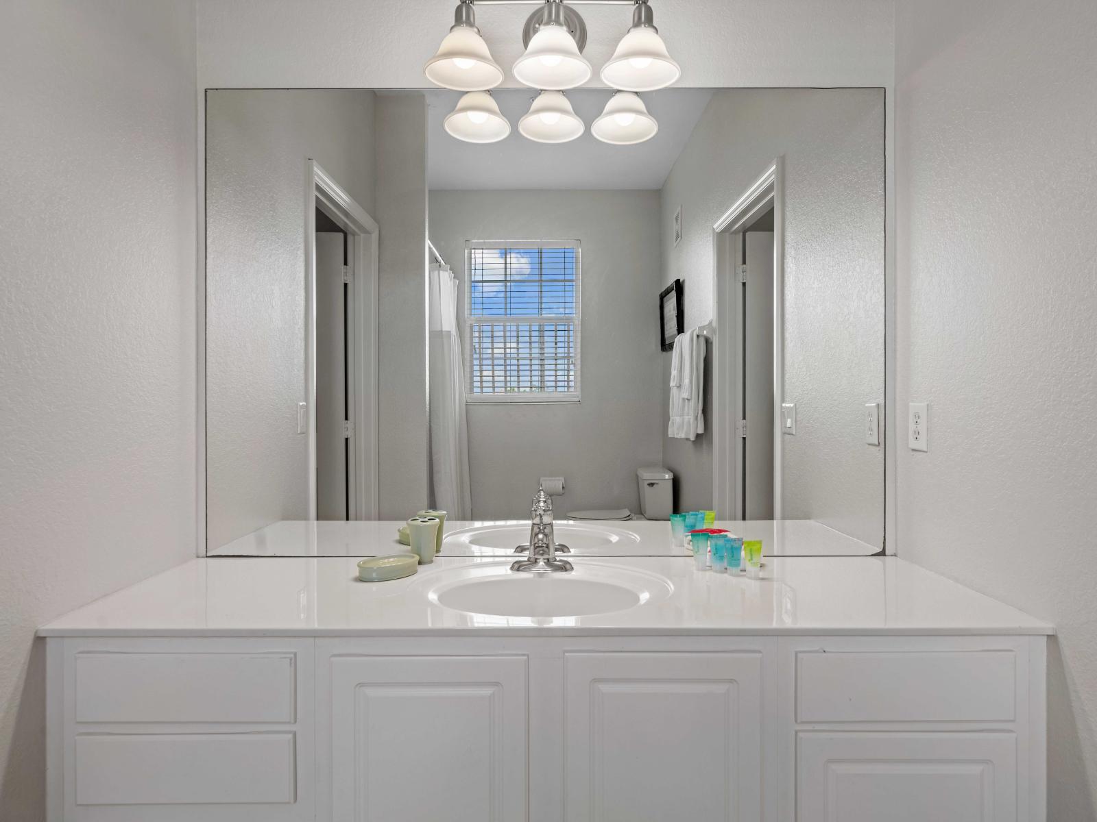 - Clean bathroom with a large mirror and single-sink vanity, perfect for your daily routine - Well-lit with modern lighting fixtures providing a comfortable space - Features a bathtub and shower combo offering versatility for relaxing baths