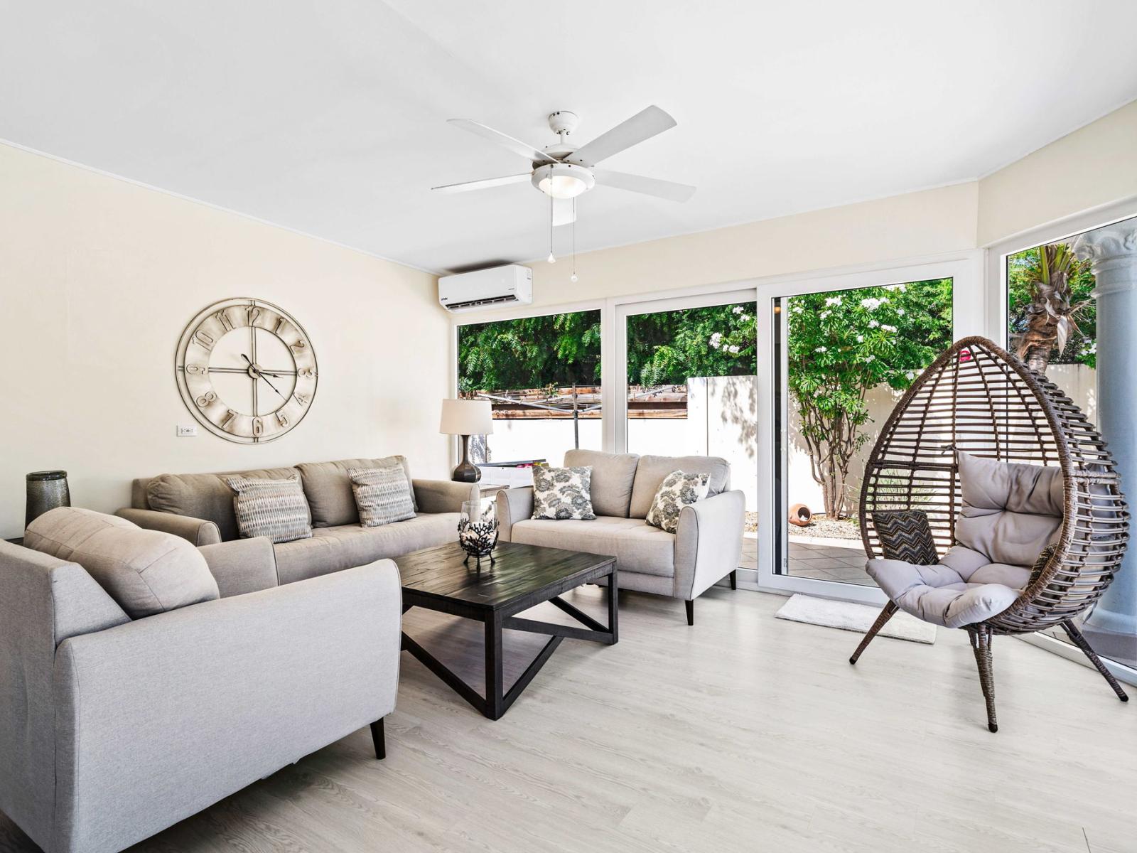 Relax in a spacious living area with plush seating and a welcoming atmosphere of the home in Noord Aruba - Sliding glass doors to the backyard with pool and plenty of combatable loungers - Perfect blend of comfort and style, ideal for unwinding