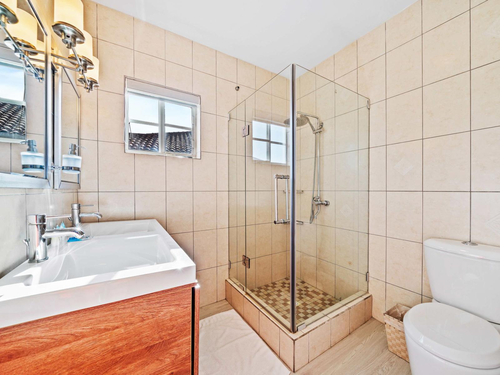 Discover relaxation and serenity in the tastefully designed bathroom - Effortlessly stylish, the bathroom features a chic vanity and upscale lighting - Spacious glass-enclosed walk-in shower area for ultimate relaxation