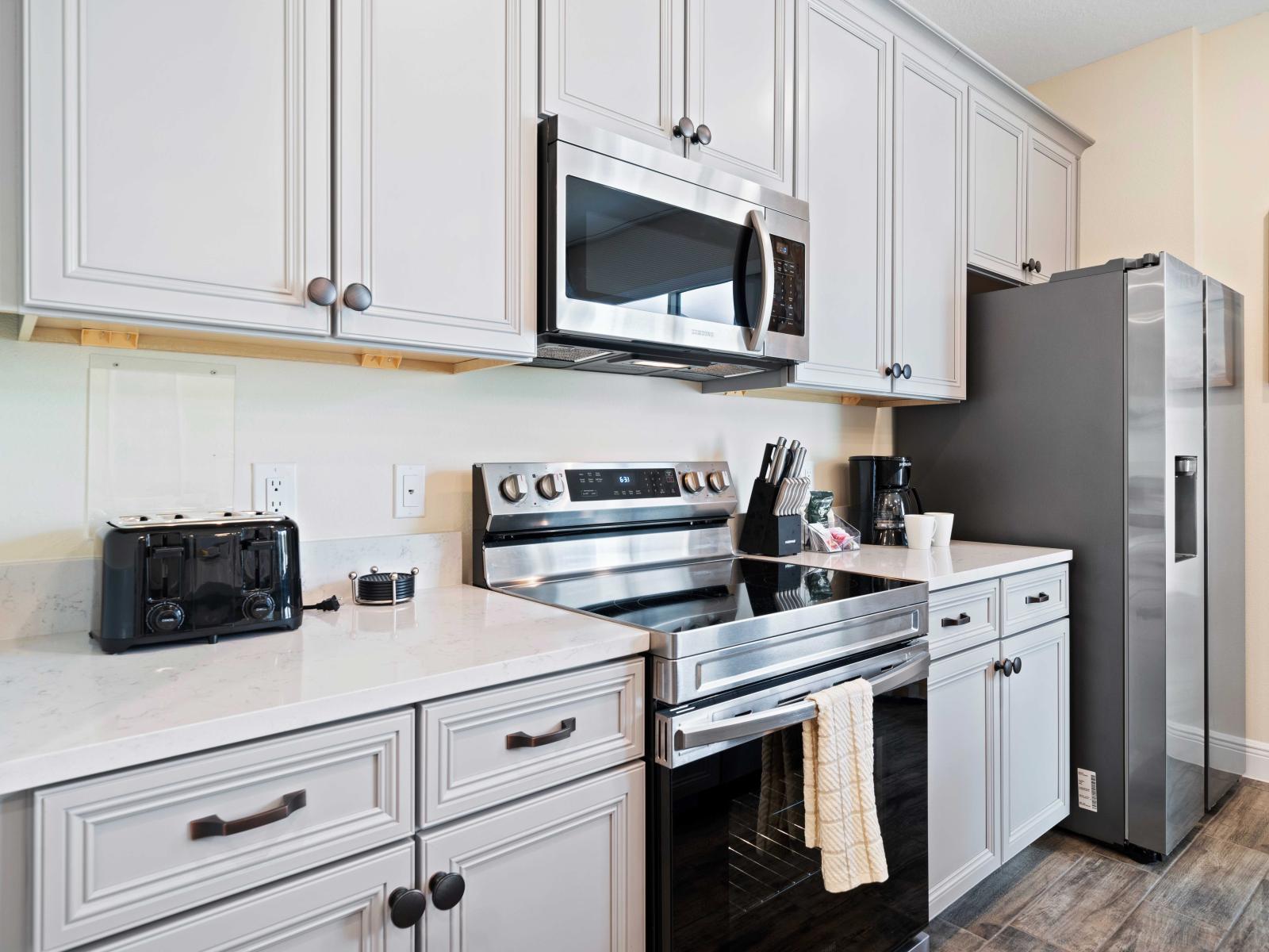 This kitchen features elegant white cabinets paired with sleek stainless steel appliances - Spacious countertop perfect for meal prep and small appliances - Convenient storage and contemporary finishes, this kitchen is both stylish and functional