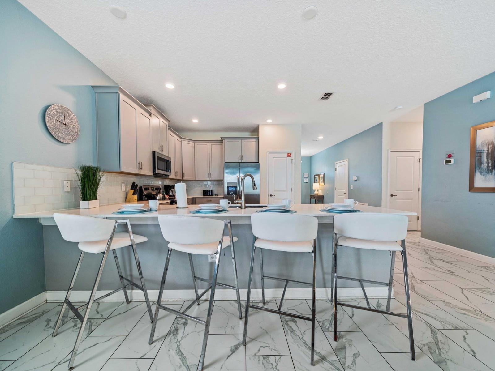 - Modern kitchen is equipped with stainless steel appliances, breakfast bar with high chairs for four - Cabinetry and marble tile flooring enhance the kitchen's elegant and contemporary design - Open layout ensures a seamless connection to dining