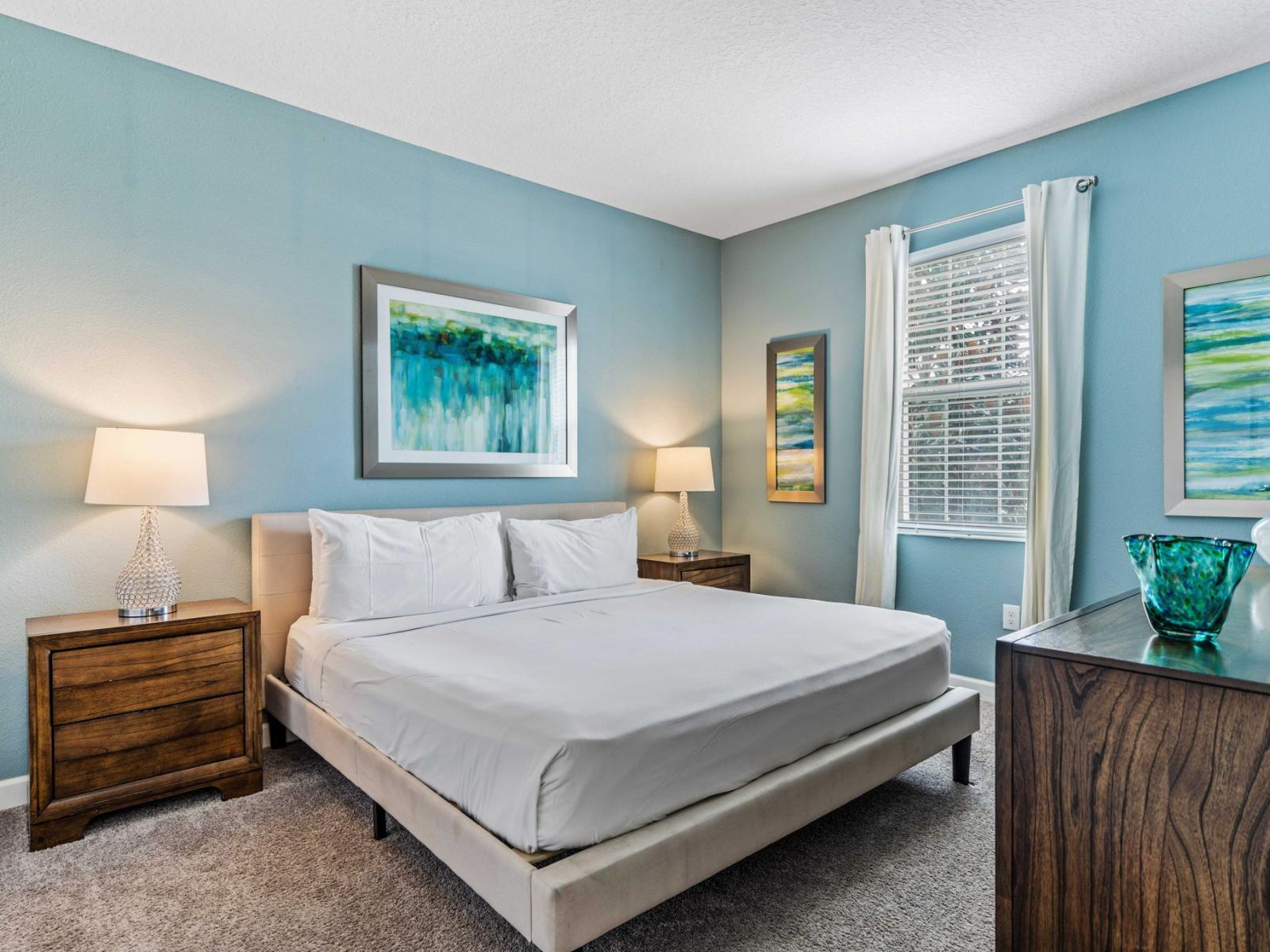 - Cozy bedroom with a modern aesthetic, featuring a plush king bed and vibrant artwork - Ample natural light fills the room through large windows - Equipped with stylish furniture, including bedside tables with lamps and smart TV for relaxation