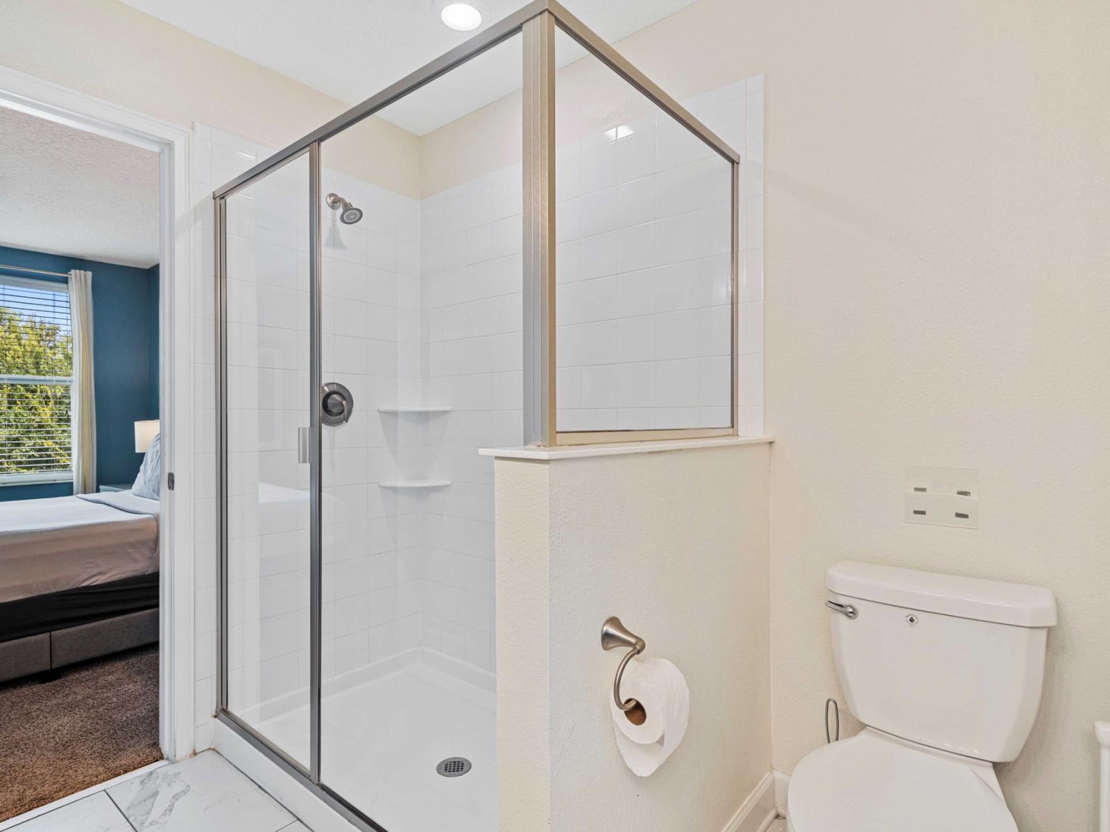 - Shower features sleek glass doors and intricate tile work, contributing to overall aesthetic appeal - Neutral color scheme that enhances the room's airy feel - Convenient shelving within the shower provides space for storing toiletries