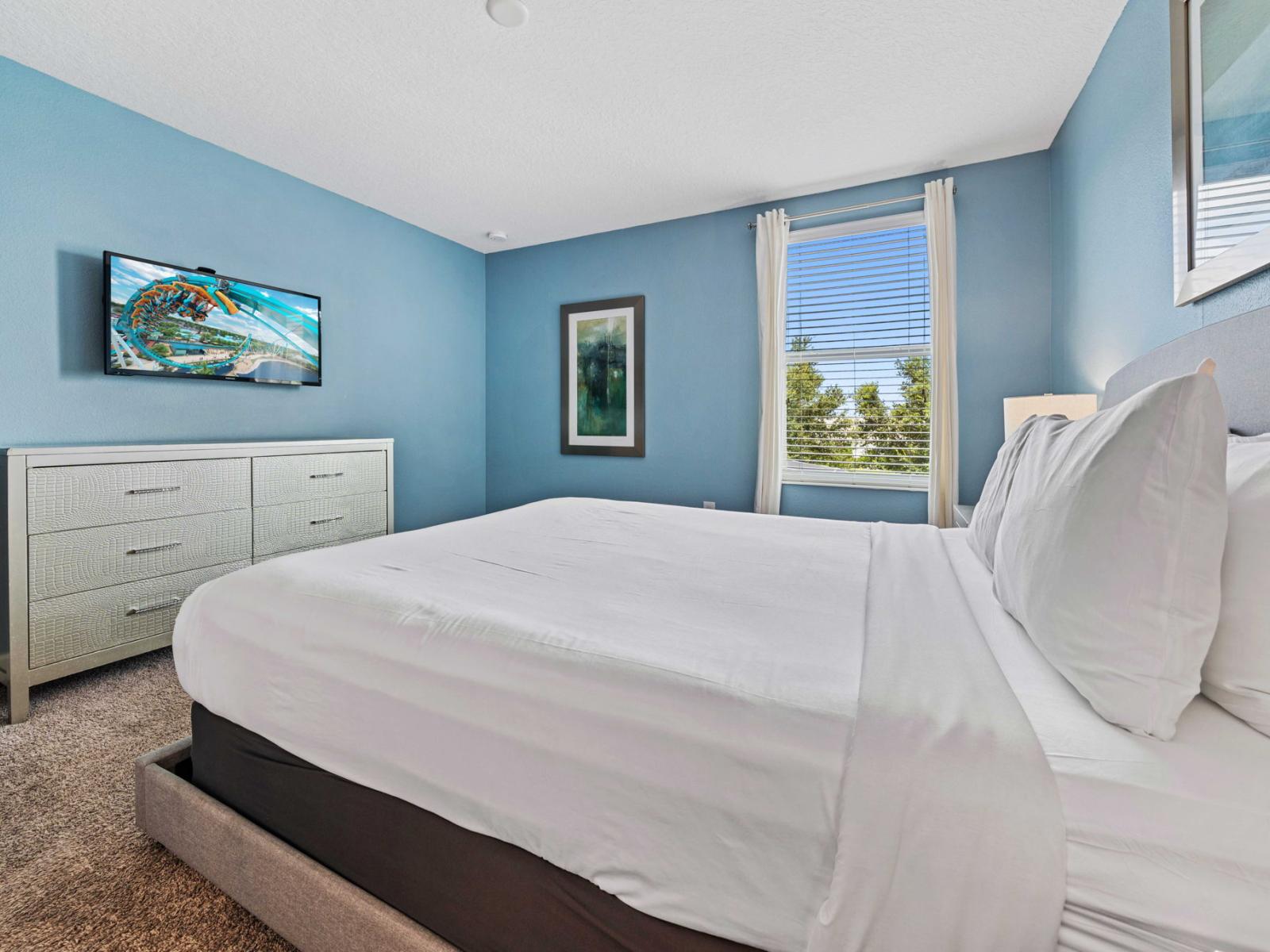 - Inviting bedroom features a queen bed, set against soft blue walls that create tranquil ambiance - Window allows natural light to pour in, illuminating the room - Furnished with a smart flat-screen TV, offering additional storage and entertainment