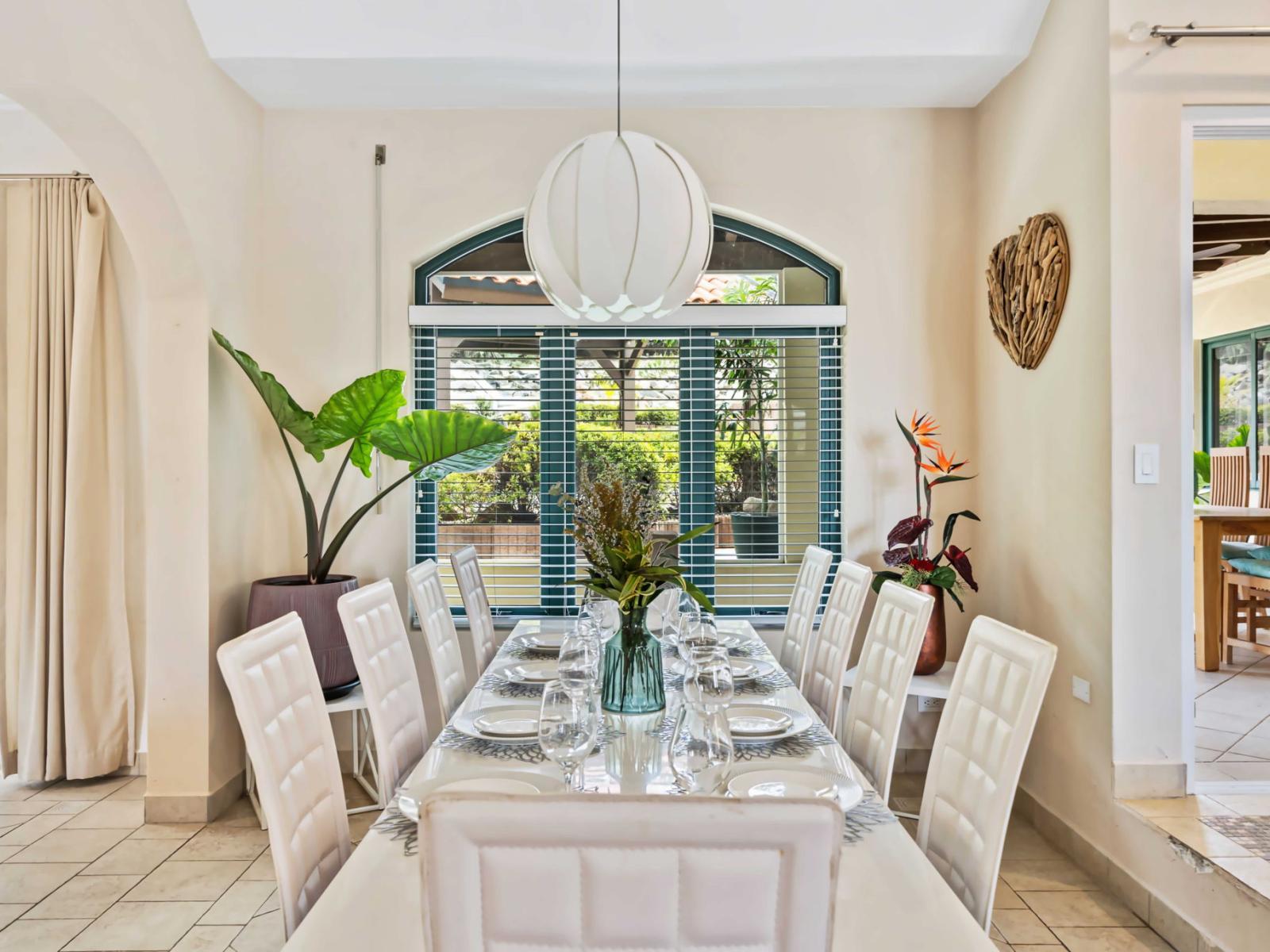 The stylish dining area boasts a large, elegant table and white chairs, perfect for gatherings - Window offering a view of the lush greenery outside - Ideal for both casual meals and formal occasions, the area enhances the villa's inviting ambiance