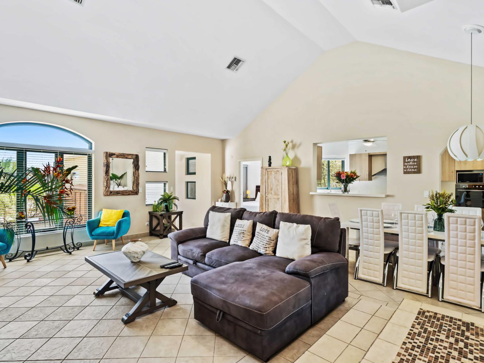 Step into this inviting living room featuring a plush, sectional sofa - Bright and airy, the space is accentuated by windows that let in plenty of natural light - The adjoining dining area seamlessly connects, making it easy to enjoy meals together