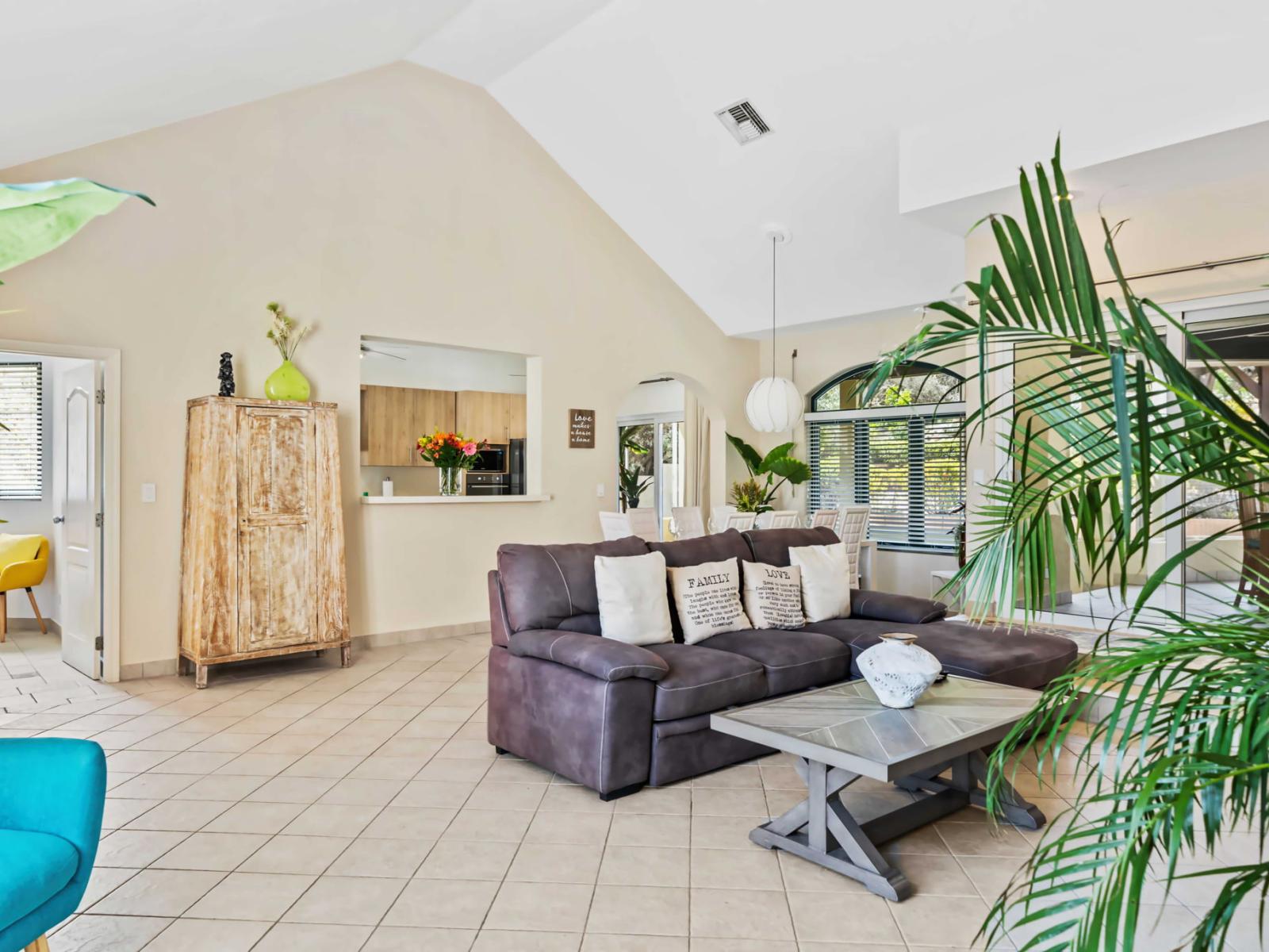 Living room includes beautiful plants and tropical accents, creating a relaxing, island vibe - Glass doors open to the patio, making it easy to enjoy indoor-outdoor living - The space is bright and airy, natural light enhancing the open feel