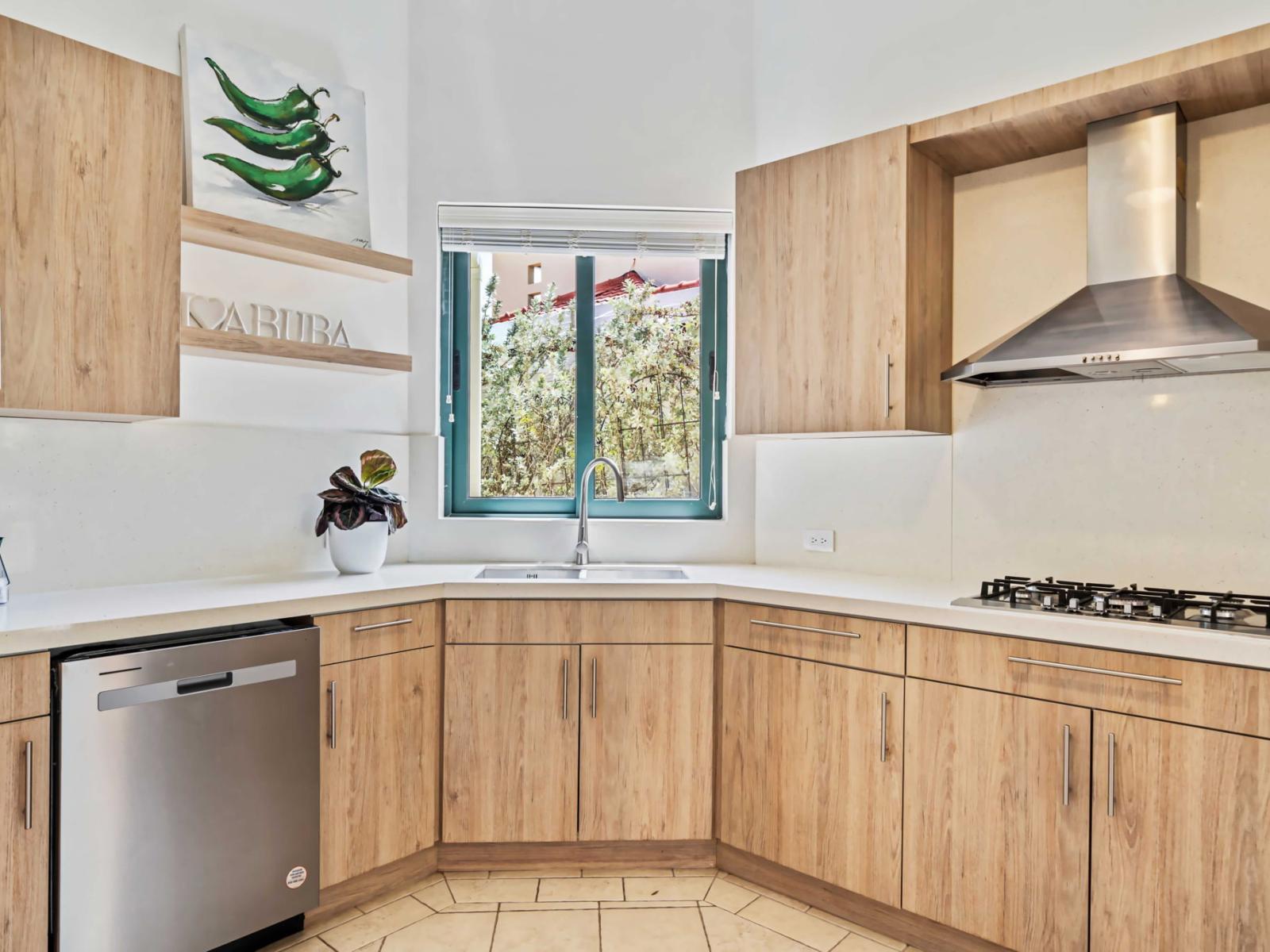 Sleek wooden cabinets and a stainless steel range hood highlight this modern kitchen - A window allows natural light to brighten the space, featuring green-themed artwork - The kitchen includes a built-in dishwasher and a compact sink for ease