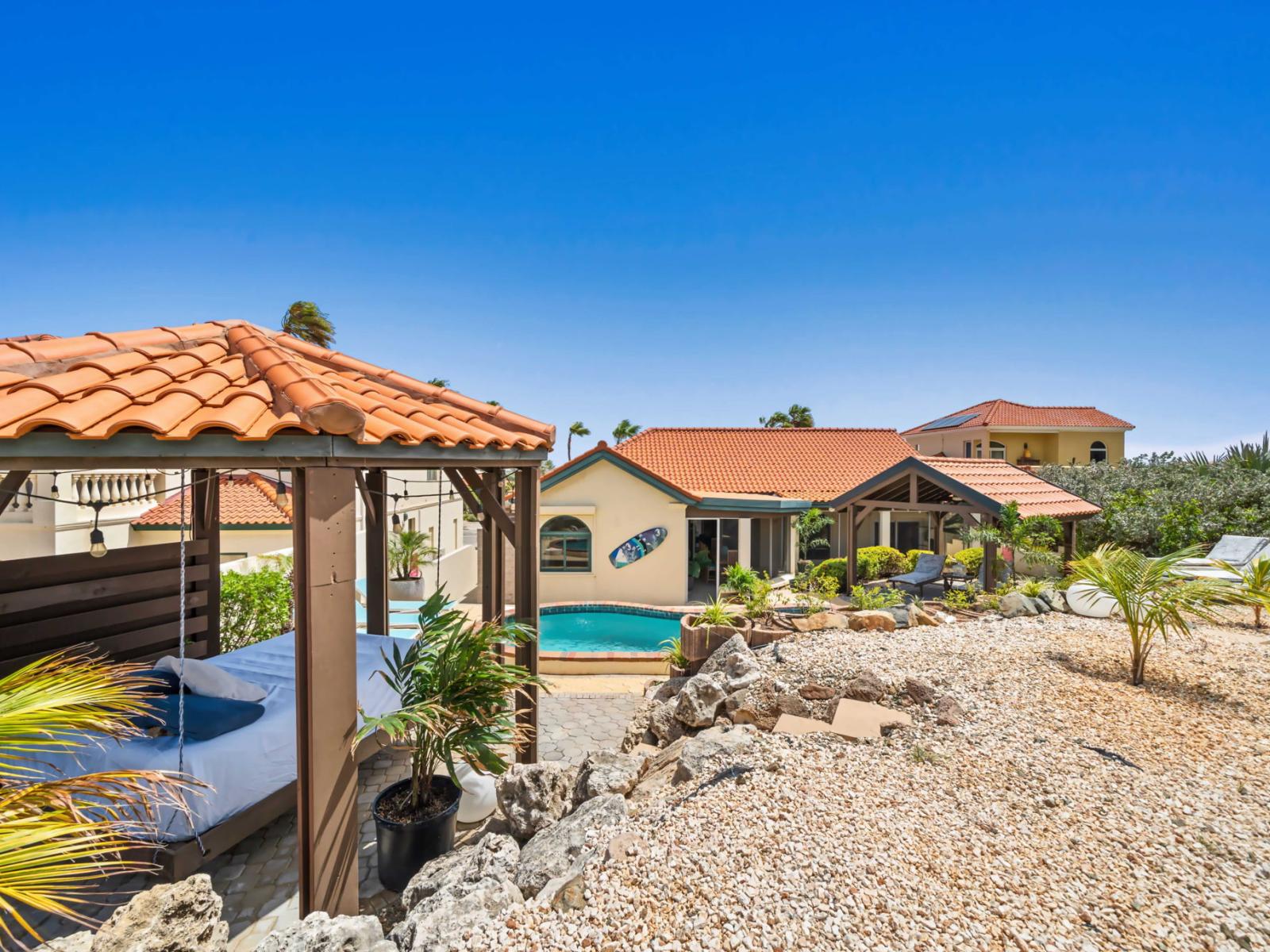 Serene retreat featuring a private pool surrounded by lush landscaping and cozy cabanas with terracotta roofs - Perfect for relaxation, sunlit lounge area and shaded seating for ultimate comfort - Ideal vacation getaway offering picturesque views