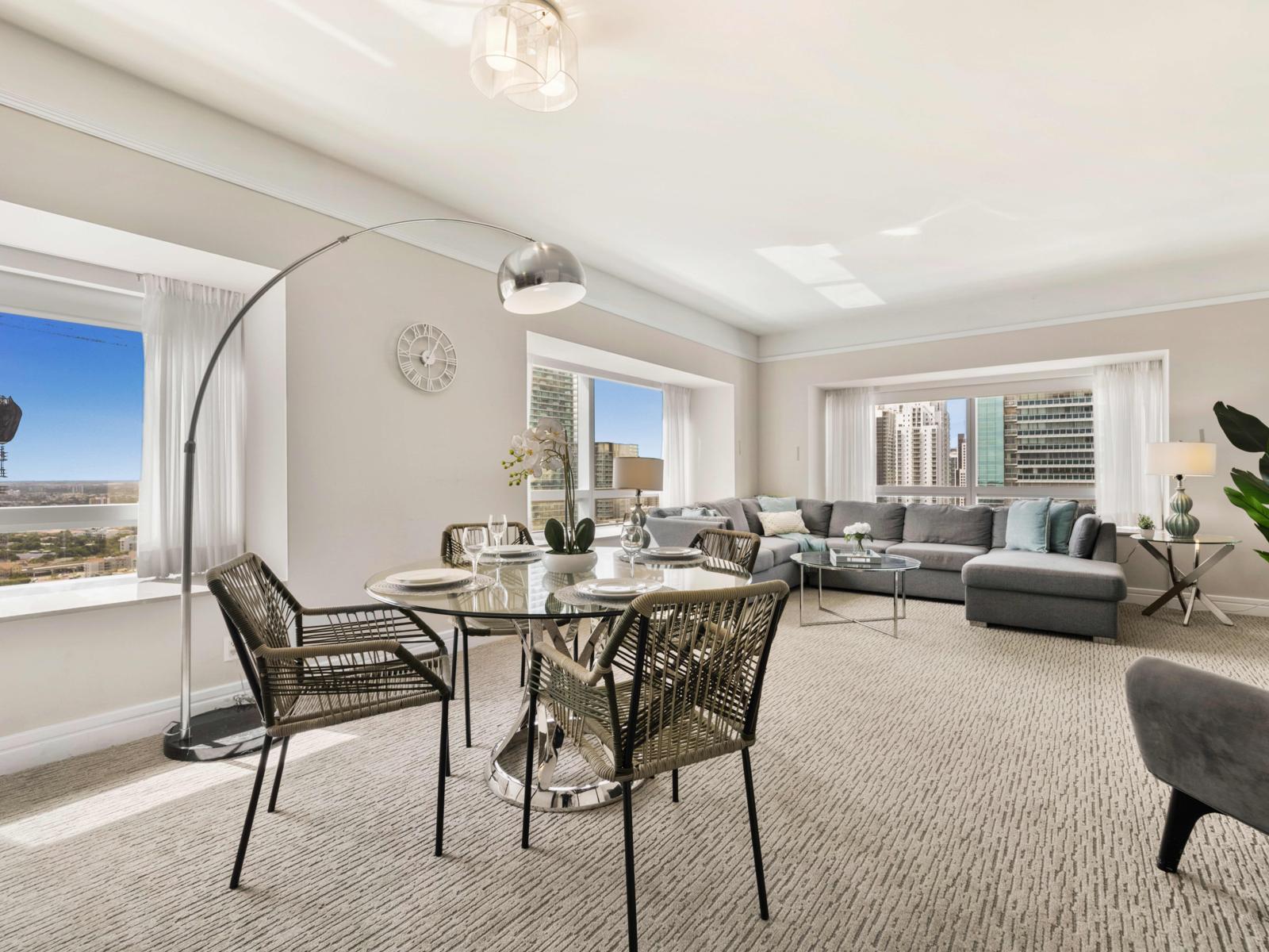 - Enjoy time with family in this sunlit living area with modern furnishings - Enjoy panoramic city views through large windows - The open-plan layout seamlessly connects the dining and living areas, creating a welcoming and airy atmosphere