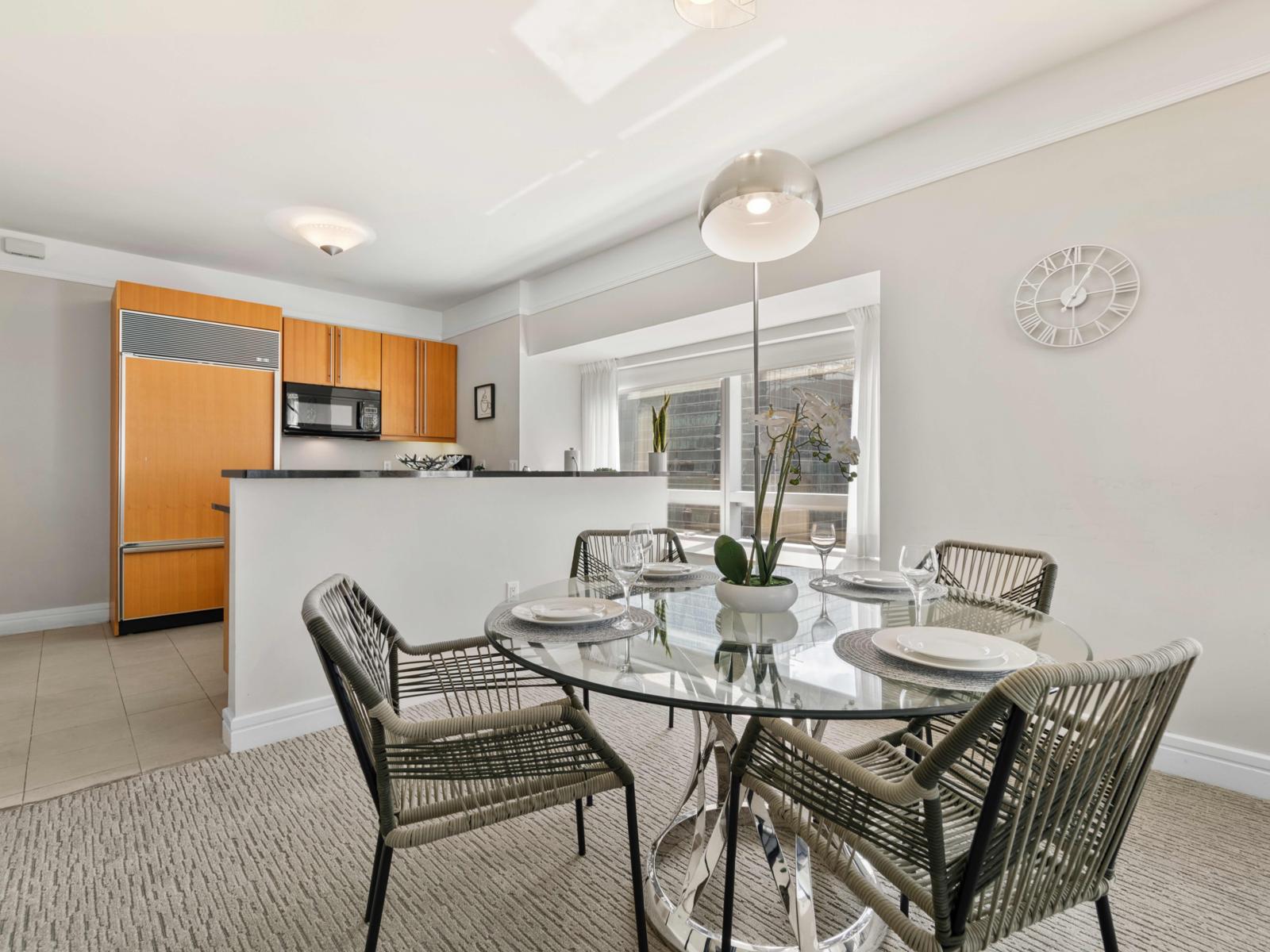 - Dine in a bright, modern area with a sleek glass table and comfortable seating for four - The open layout seamlessly connects with the kitchen, ideal for socializing - Natural light creates a warm, inviting atmosphere for every meal