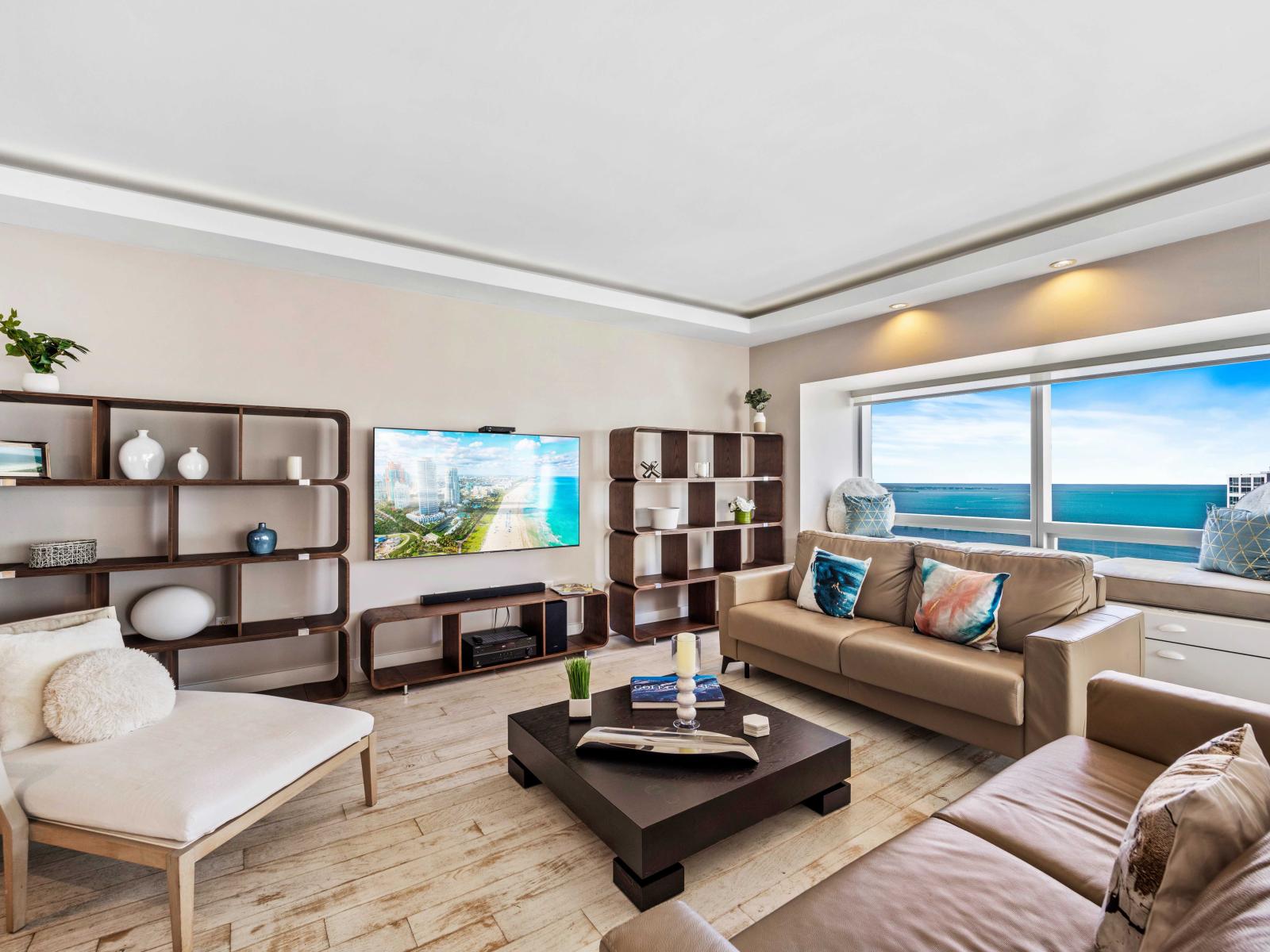 - Spacious living area with contemporary furnishings, perfect for relaxing - Large windows offer stunning views of the ocean, bringing natural light and a serene atmosphere - Features include a flat-screen TV, comfy seating, and elegant decor