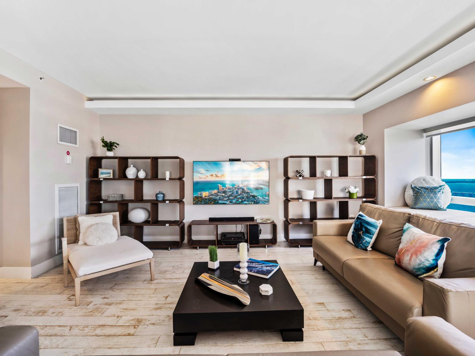 - Stylish living room with decor and large flat-screen TV, perfect for relaxation - Large windows offering breathtaking ocean views filling the space with natural light - Comfortable seating area with chic furnishings creating a cozy atmosphere