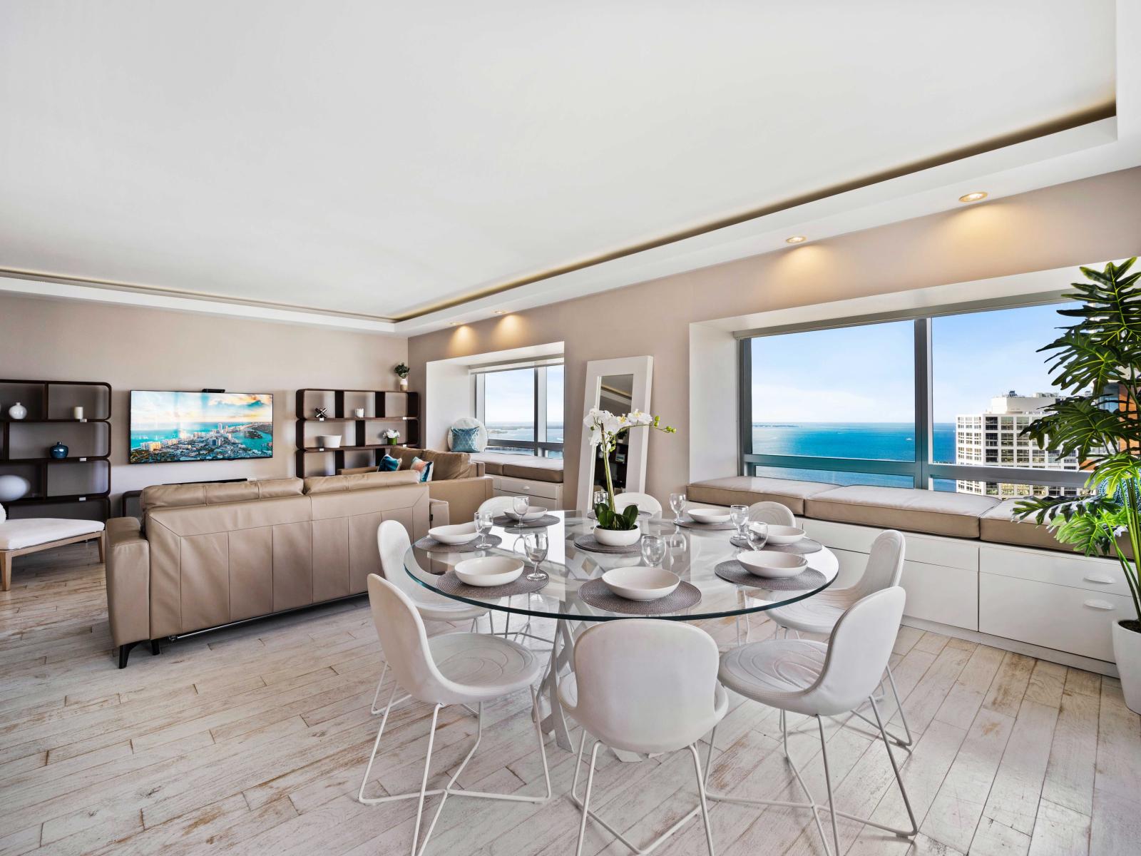 - Elegant open-concept dining and living area offering stunning ocean views - Modern dining table set for eight, perfect for enjoying meals in a bright and airy space  - Comfortable seating areas, creating an inviting atmosphere for relaxation