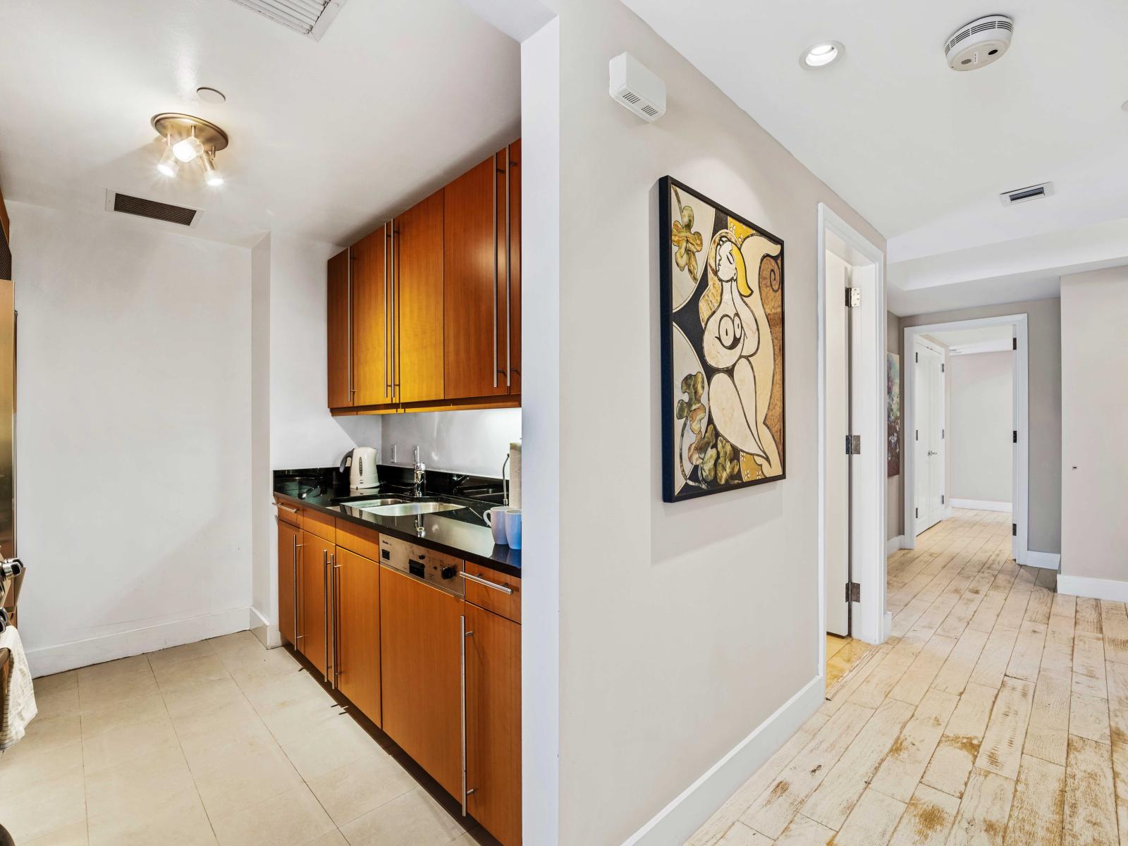 - Fully equipped kitchen with modern appliances and storage  perfect for preparing meals - Welcoming hallway leading to the kitchen adorned with stylish artwork - Convenient layout with easy access to all amenities ensuring a seamless experience