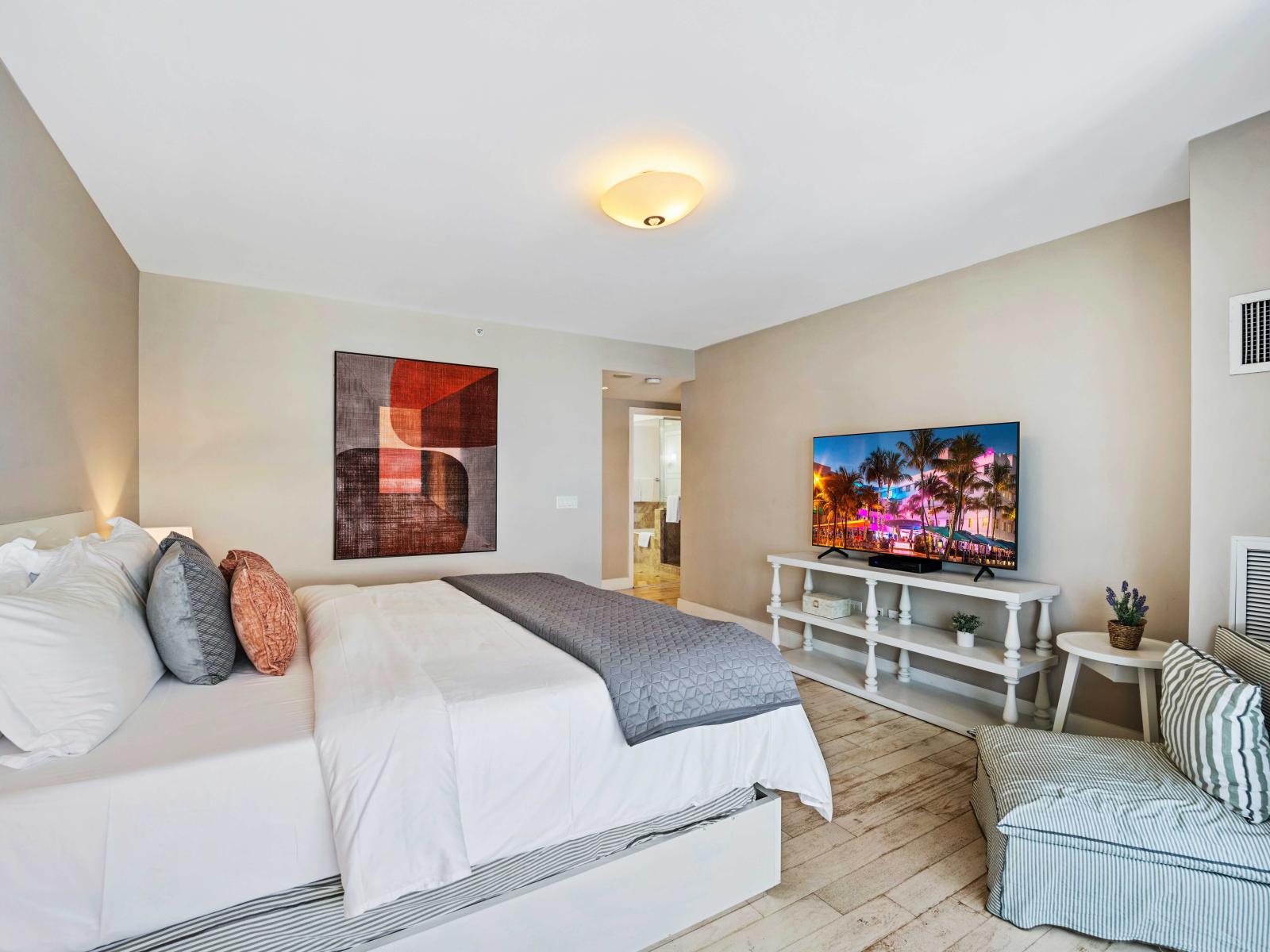 - Spacious bedroom featuring a luxurious king-sized bed with plush linens for ultimate comfort - Large flat-screen TV and cozy seating area perfect for relaxing - Modern decor with tasteful artwork creating a stylish and inviting atmosphere