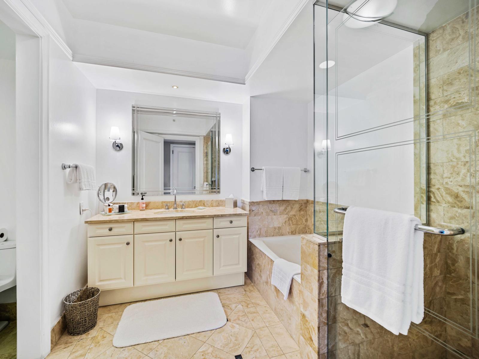 - Luxurious bathroom featuring a double vanity with modern fixtures - Elegant design with a large glass-enclosed walk-in shower and a separate bathtub - Well-lit space with a large mirror and plush towels, providing a refreshing experience