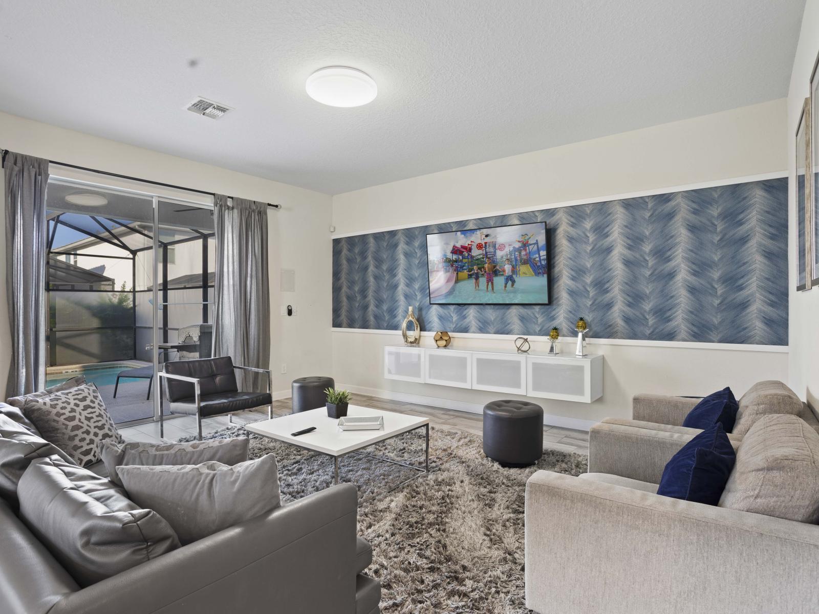 - Relax in a modern living area featuring comfortable seating and sleek design - Large windows and sliding doors offer natural light and poolside views - Ideal for relaxation, featuring a smart TV and contemporary décor