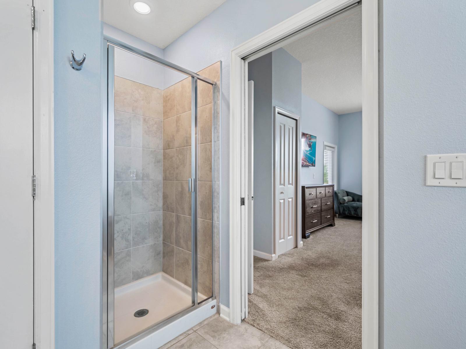 - Spacious walk-in shower with sleek glass doors and tiled walls for a modern look   - Convenient access from the bedroom with neutral tones creating a calming atmosphere   - Bright and airy layout with easy flow between the bedroom and bathroom area