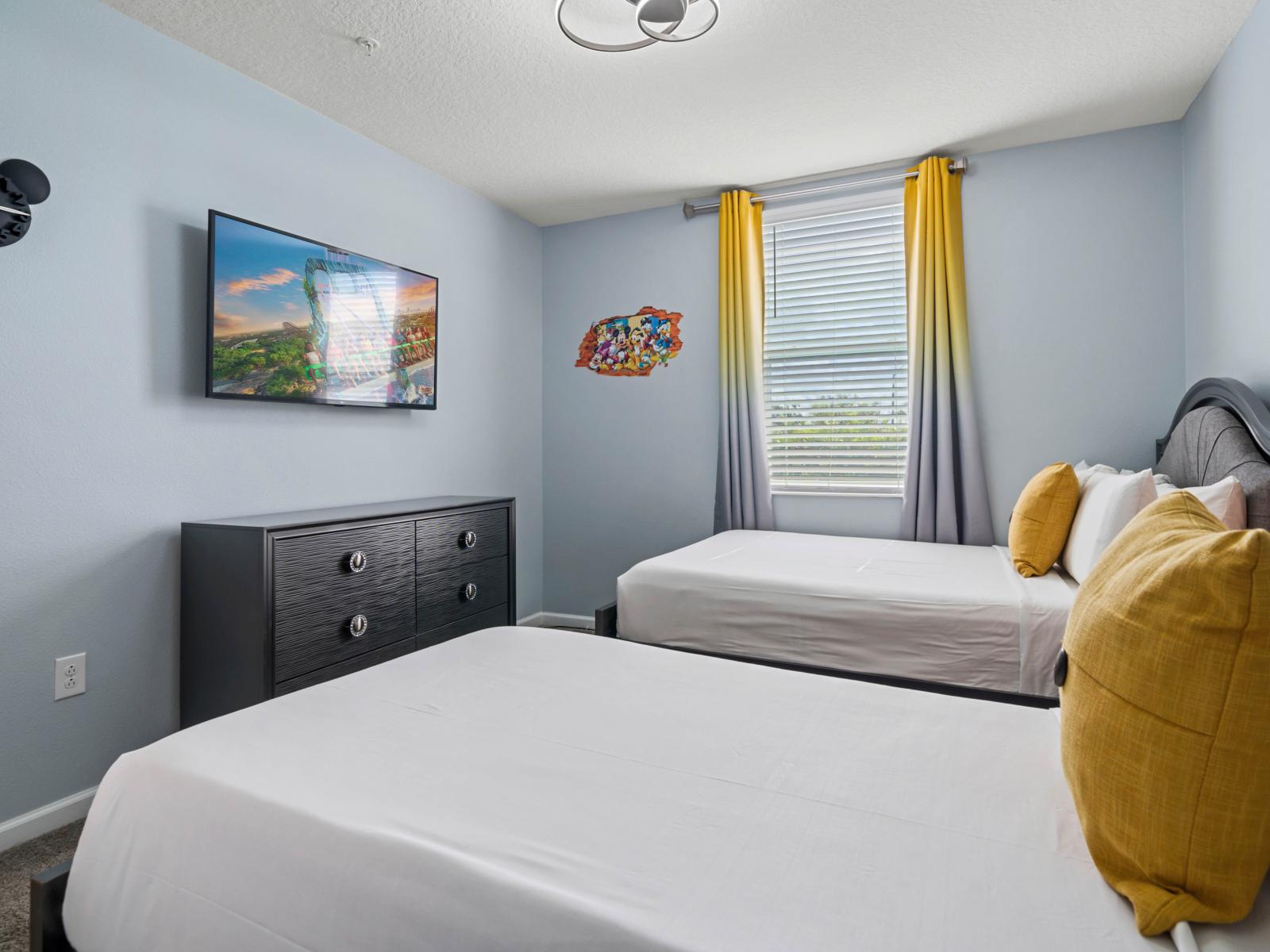 - Bedroom offers one double and one single bed with vibrant yellow accent pillows - A large flat-screen TV mounted on the wall for entertainment, along with a sleek dresser for additional storage - Bright decor featuring playful Disney-themed accents