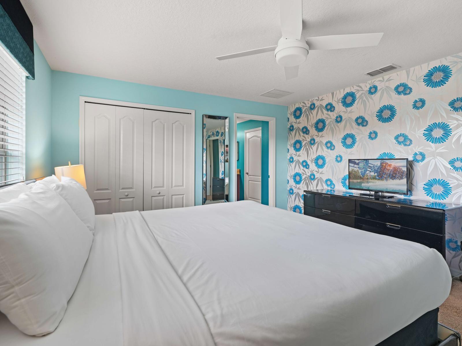 - Bright bedroom with a king-size bed, crisp white linens, and a bold turquoise floral accent wall - Large closet and sleek black dresser with a smart TV for added convenience - Spacious and airy with natural light highlighting the modern decor