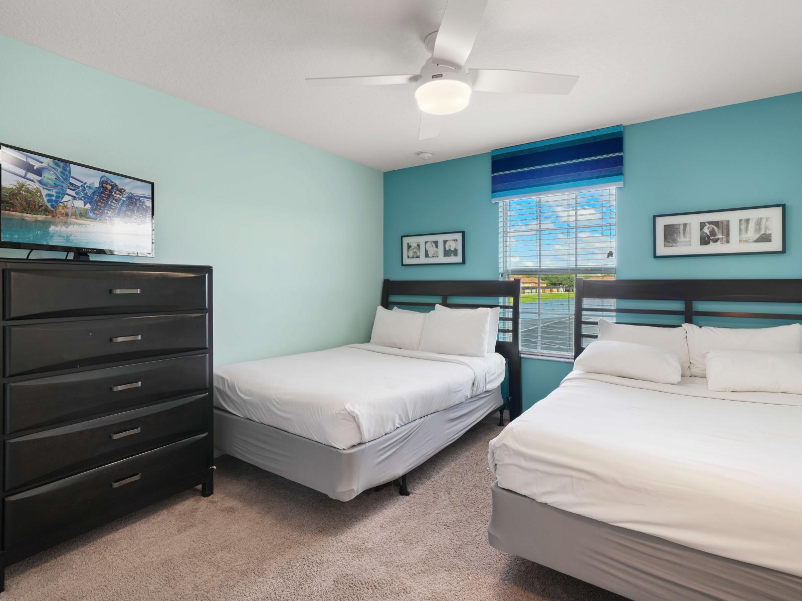 - Cozy bedroom with a double and single bed, perfect for multiple guests - Light turquoise walls, modern black dresser, and ceiling fan create a fresh look - Large window with striped accents brings in natural light, creating a welcoming atmosphere