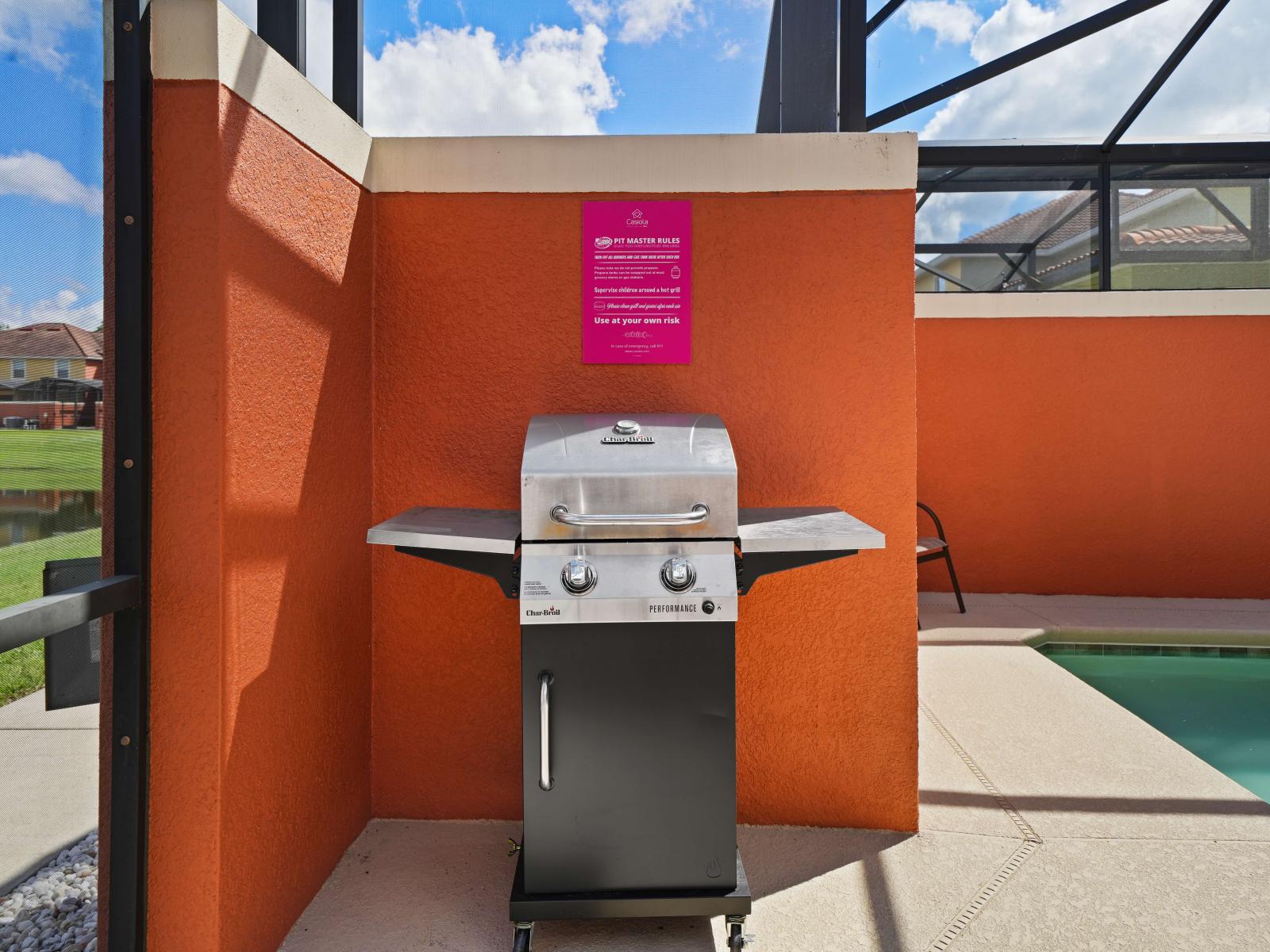 - Outdoor BBQ grill set against a bright orange wall, perfect for poolside cooking and gatherings - Compact yet functional, with plenty of space for grilling - Beautiful scenic view of the nearby water adds to the relaxing, outdoor dining experience