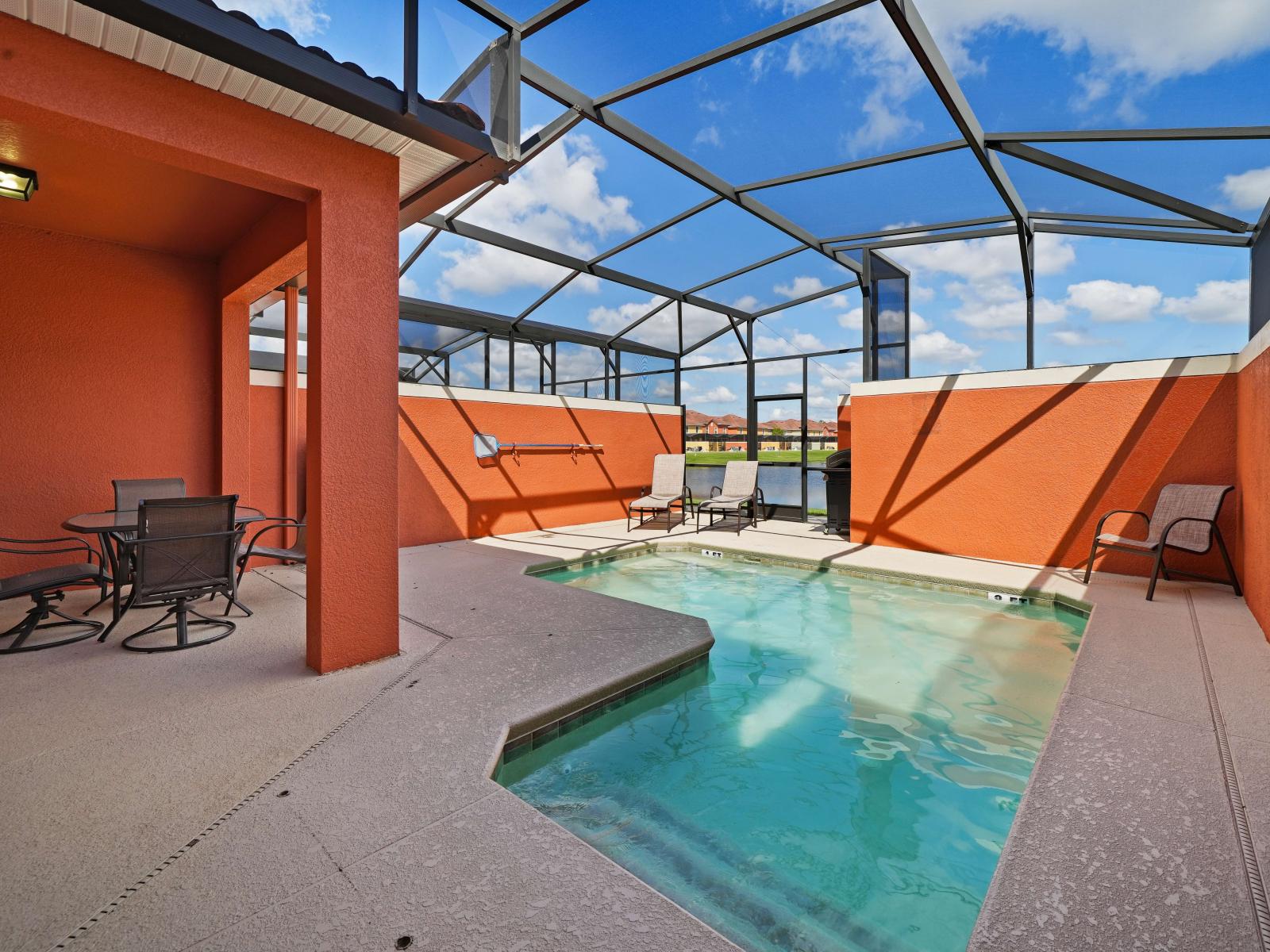 - Outdoor pool area with a screened enclosure, offering both sun and shade for relaxation - Vibrant orange walls and a private pool create a fun and inviting atmosphere - Seating area for dining and lounge chairs for sunbathing enhance the experience