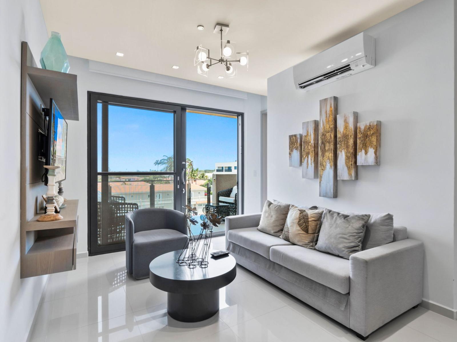 - Unwind in this stylish living area with elegant decor and plenty of natural light - Large glass doors open up to the balcony, merging indoor and outdoor living - A perfect spot to relax with cozy seating and a smart TV for entertainment