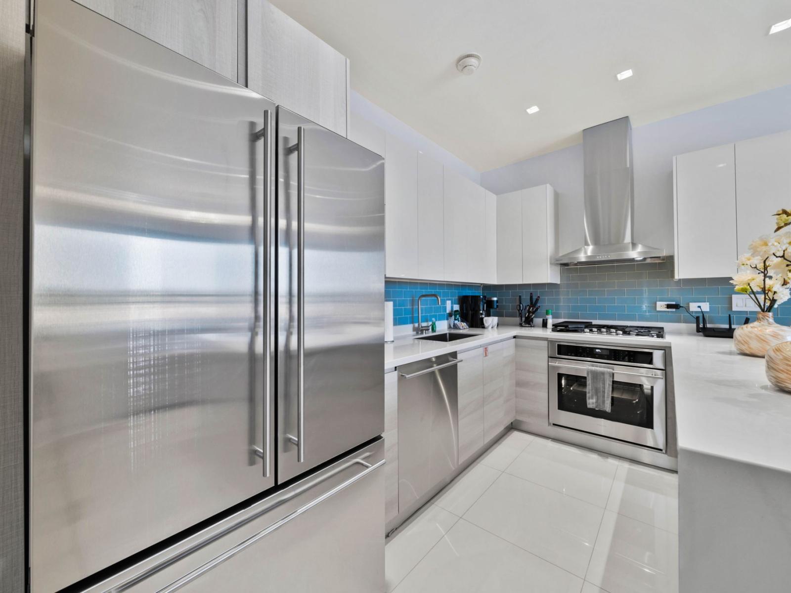 - Sleek, modern kitchen with stainless steel appliances and spacious countertops - A bright and inviting space for cooking and entertaining during your stay - Fully equipped for all your culinary needs with a stylish blue backsplash