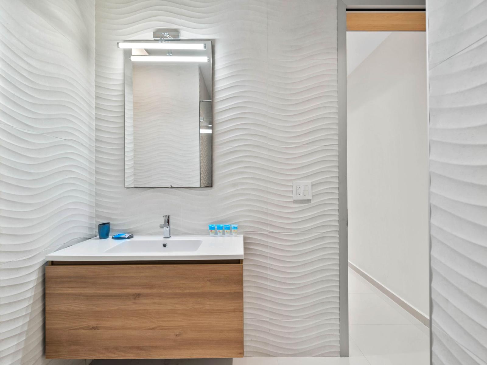 - Glorious vanity area with modern lighting and  plenty of counter space - Textured walls add a stylish touch to this minimalist bathroom - Perfect space for getting ready for a night out or unwinding after a busy day