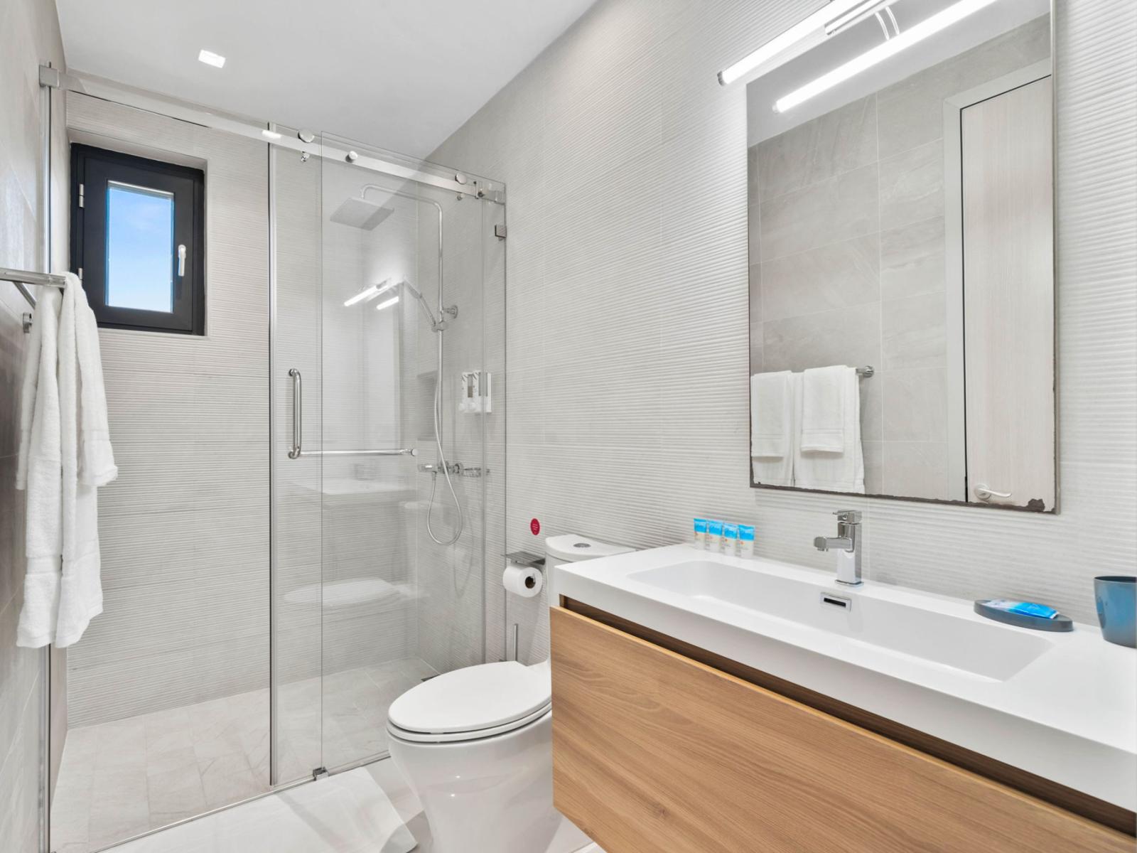 - Step inside this bright & modern bathroom featuring a spacious glass enclosed walk-in shower - Stylish vanity with plenty of storage and natural light from the window - A perfect space to refresh and relax in the comfort of your stay.