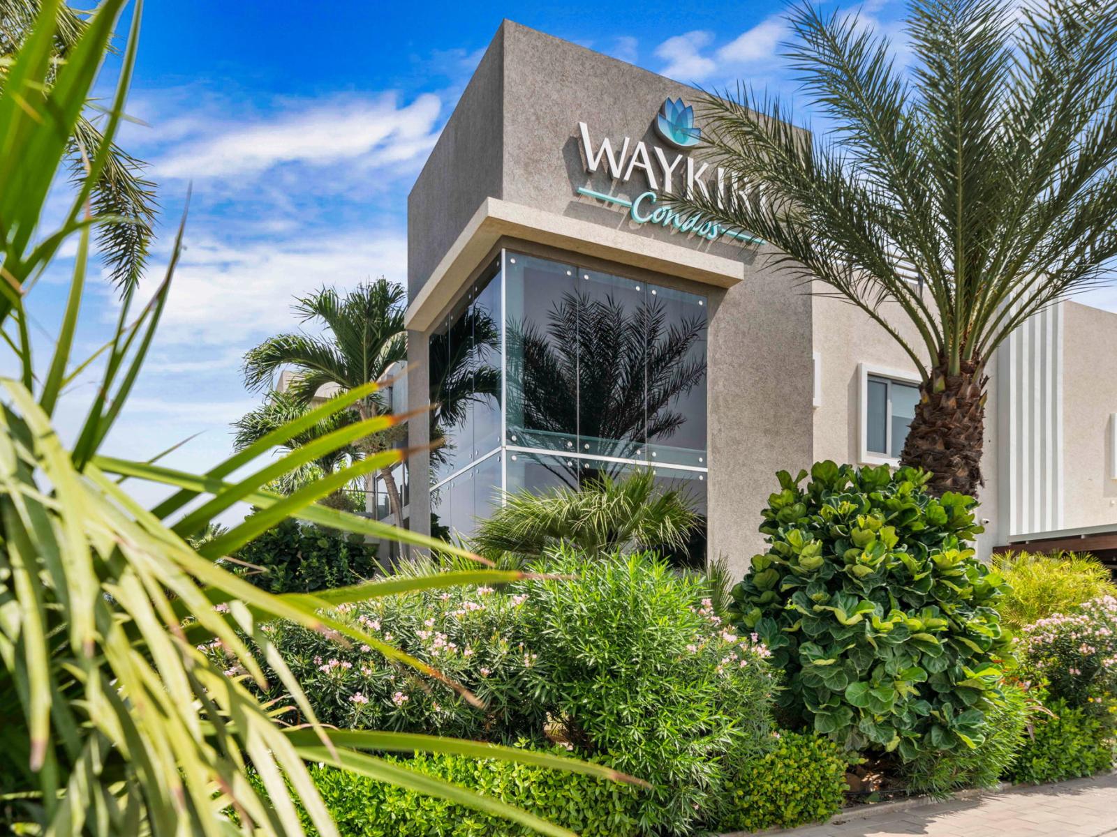 The modern exterior of Waykiri Condos, surrounded by lush greenery, offers a welcoming and luxurious stay in a tropical setting.