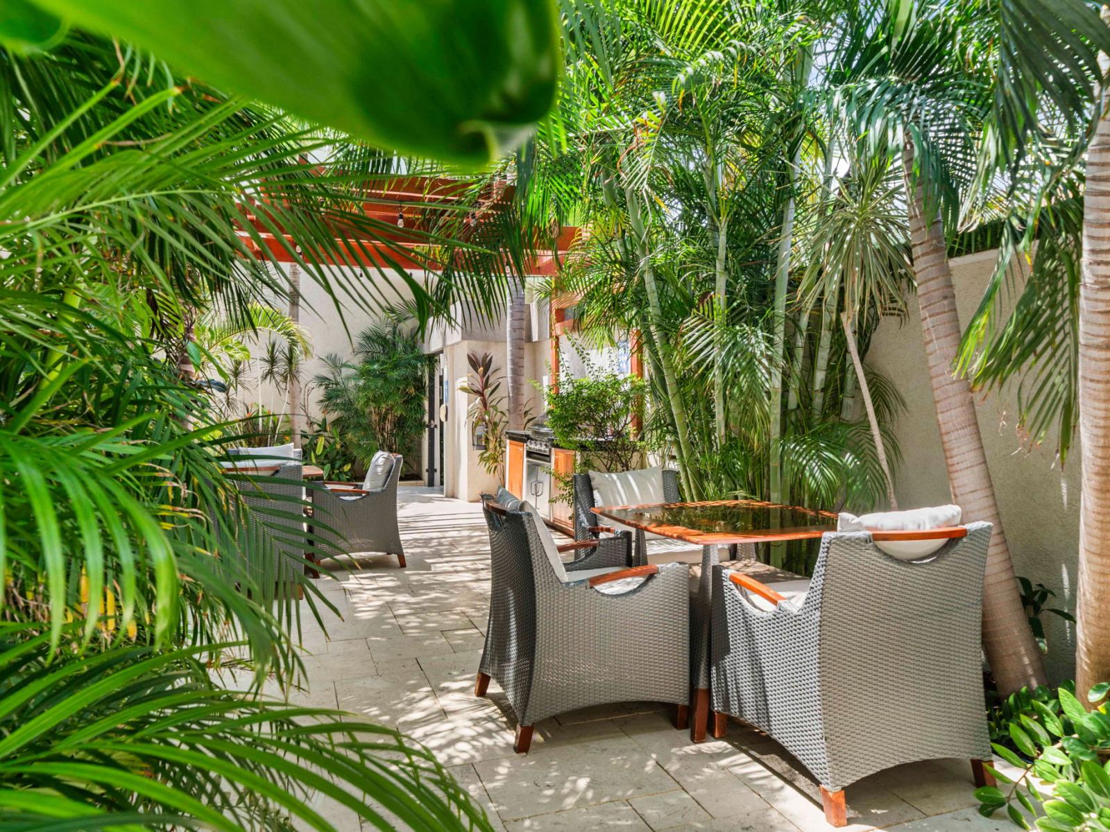 - Lush outdoor seating area surrounded by tropical plants for a peaceful retreat - Perfect for outdoor dining, shaded by greenery for added comfort - A beautiful spot for intimate gatherings or relaxing with a good book