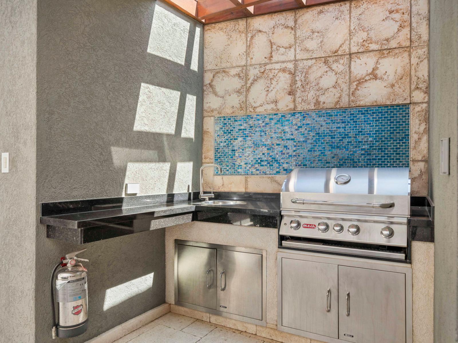 - Well-equipped outdoor grill station with stainless steel appliances - Chic design featuring a vibrant blue mosaic backsplash, adding a modern flair - Perfect for cooking up a delicious meal while enjoying the outdoor ambiance