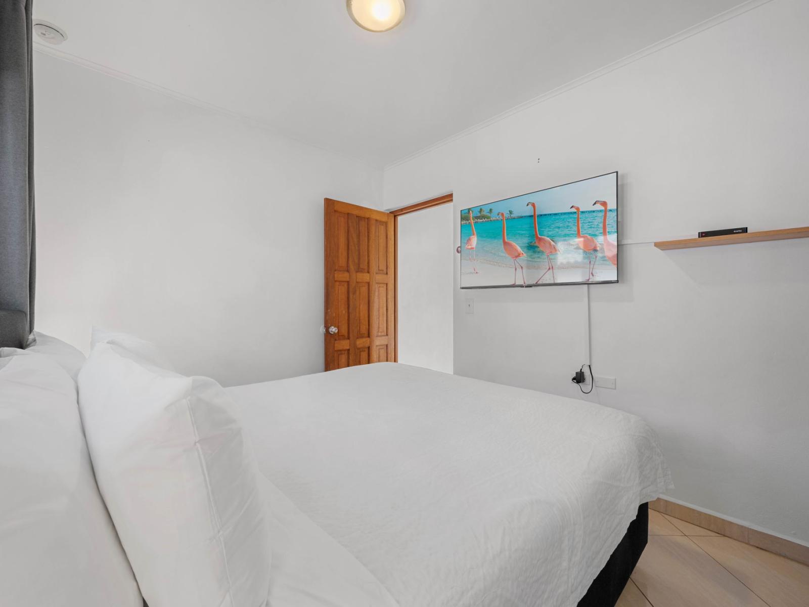 - Cozy and stylish bedroom featuring a plush king-size bed with crisp white linens - Catch your favorite shows on the wall-mounted smart TV or relax in the serene ambiance - Perfect retreat to recharge after a day of island adventures