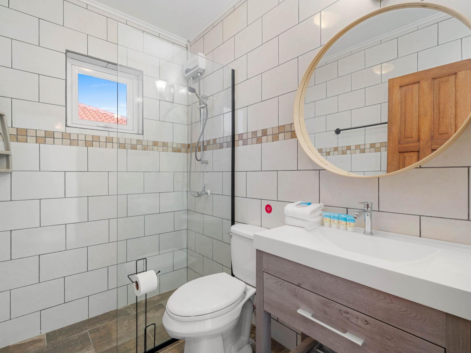 - Spa-like bathroom with elegant tilework and a spacious glass-enclosed shower - Enjoy complimentary toiletries, fresh towels, and a well-lit, modern vanity - Clean and inviting space designed for relaxation and rejuvenation