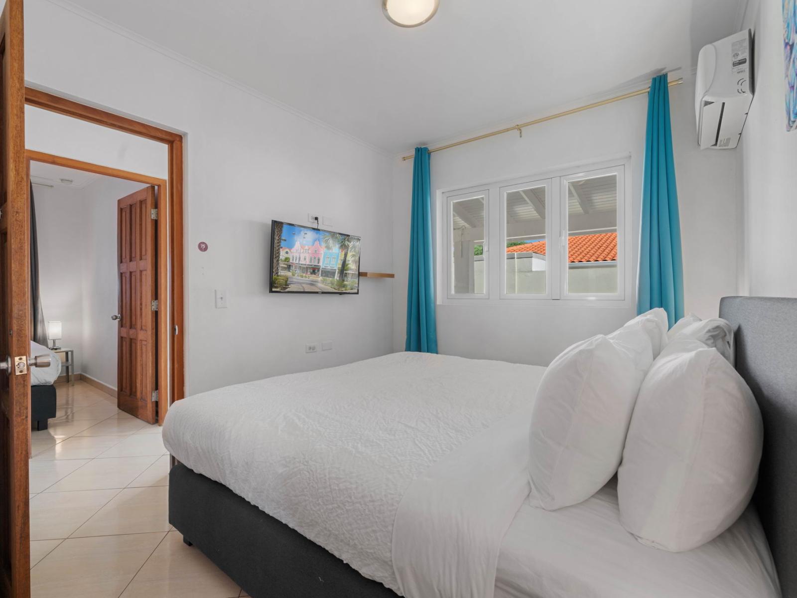 - Bright and vibrant bedroom with a king-size bed and charming accents - Natural light pours through the large windows, creating a warm and inviting atmosphere - Relax in comfort with a smart TV, air conditioning, and fresh, colorful decor