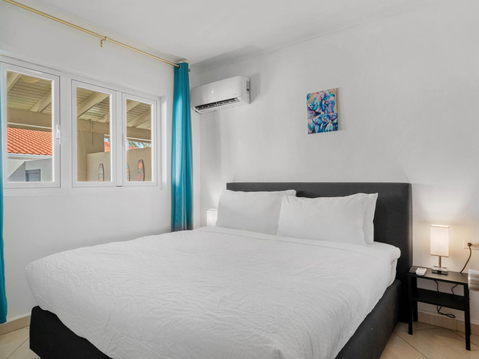 - Cozy bedroom featuring a comfortable king-size bed and soft white linens - Bright natural light and vibrant curtains create a cheerful yet serene ambiance - Equipped with air conditioning and nightstands for your convenience and comfort