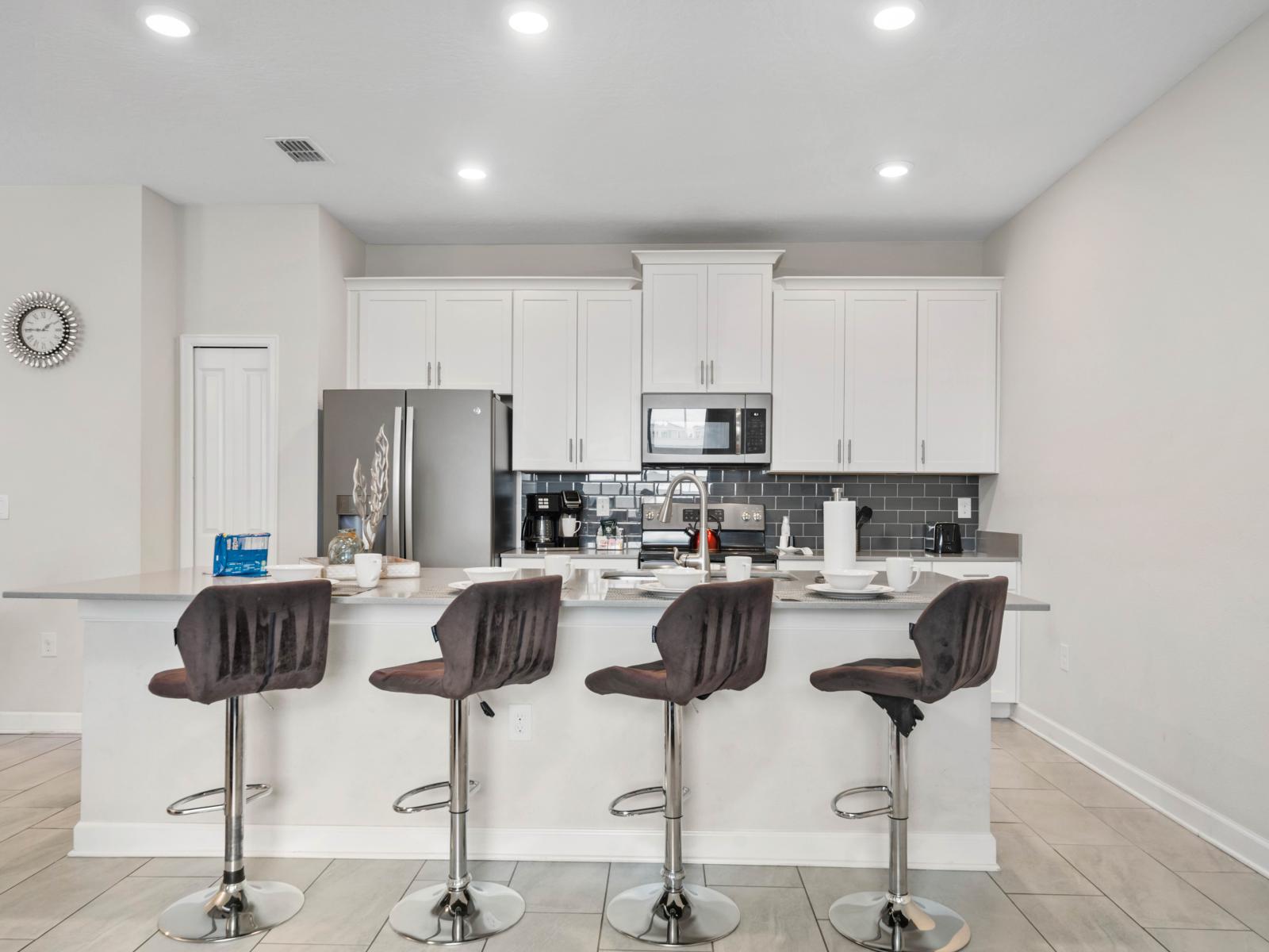 Gather & Dine: The inviting countertop table and high chairs offer a cozy spot for meals and conversations, making this kitchen the heart of your Charming 4-Bedroom Apartment.