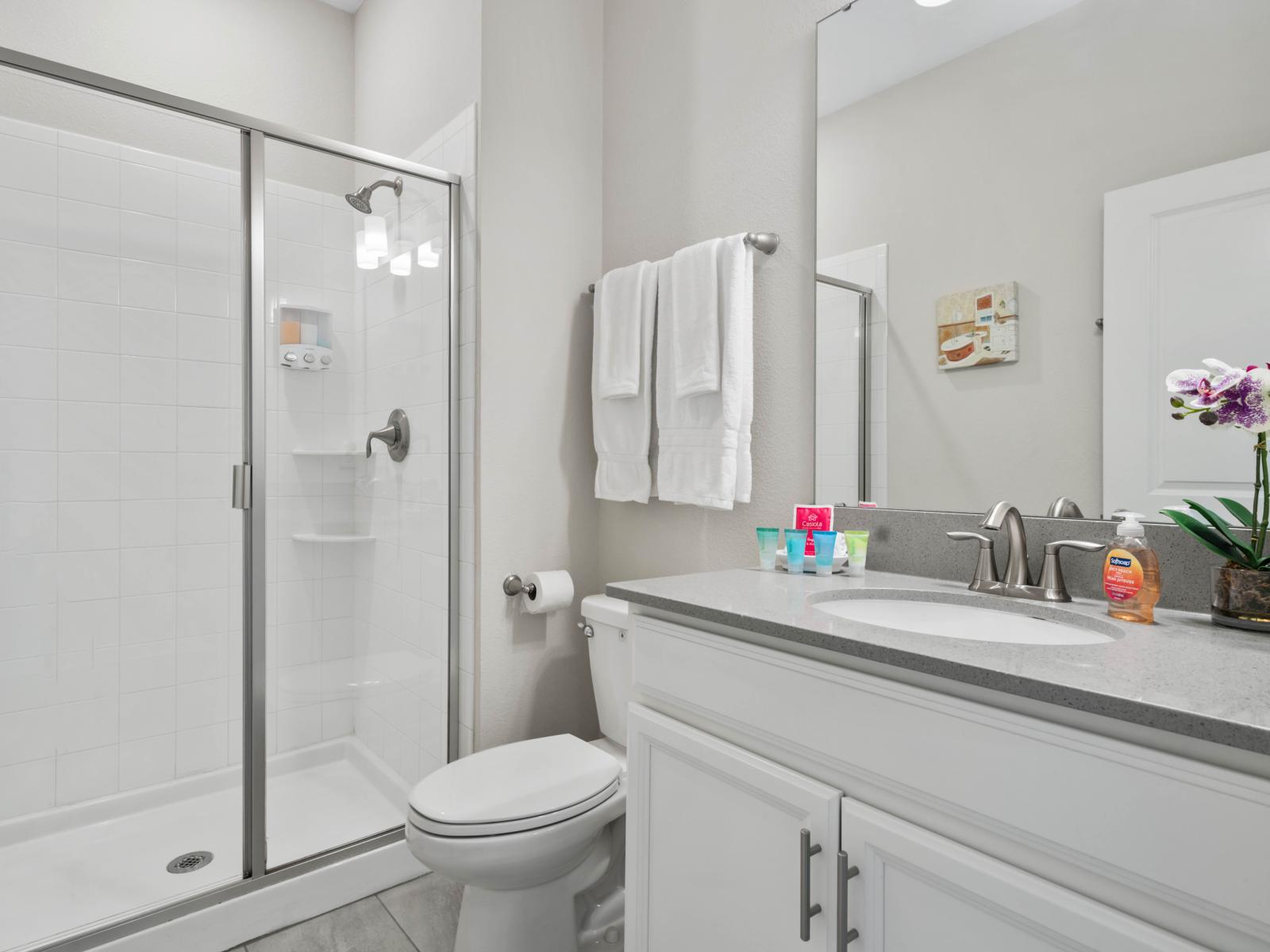 Bright & Inviting: This beautifully lit bathroom boasts a walk-in shower, offering a refreshing start to your day in our Charming 4-Bedroom Apartment.