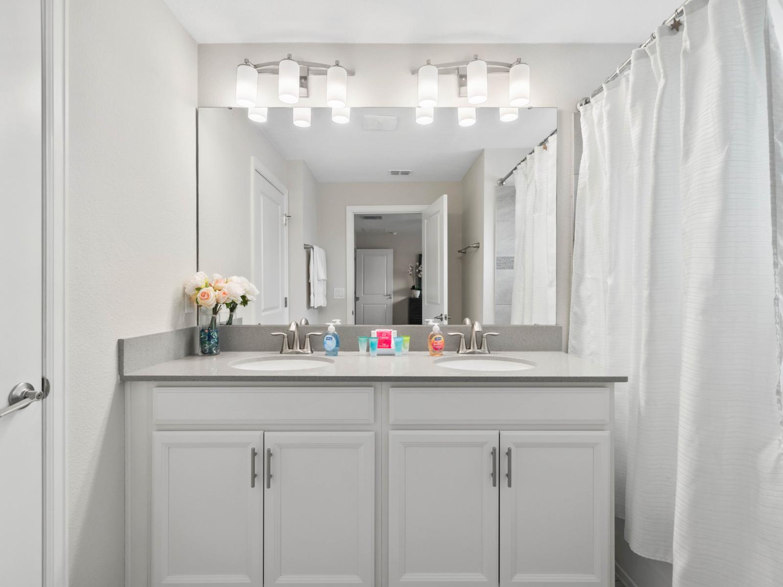 Bright & Inviting: This beautifully lit bathroom boasts a walk-in shower, offering a refreshing start to your day in our Charming 4-Bedroom Apartment.