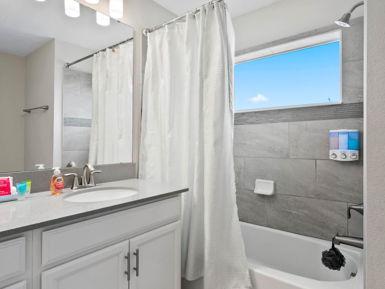 Bright & Inviting: This beautifully lit bathroom boasts a walk-in shower, offering a refreshing start to your day in our Charming 4-Bedroom Apartment.