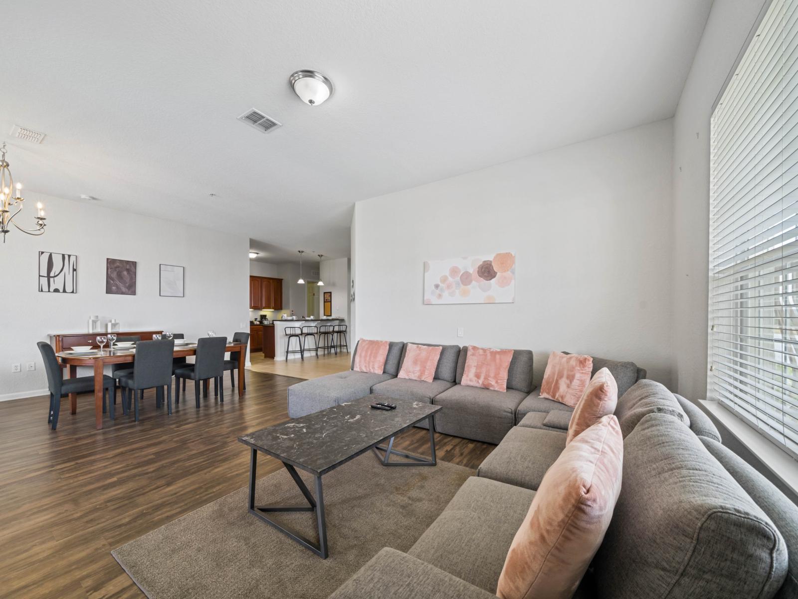 - Inviting living room with a plush sectional sofa, perfect for lounging or movie nights - Open floor plan connects seamlessly to the dining area & kitchen for easy interaction - Enjoy the bright & airy ambiance with large windows & tasteful accents